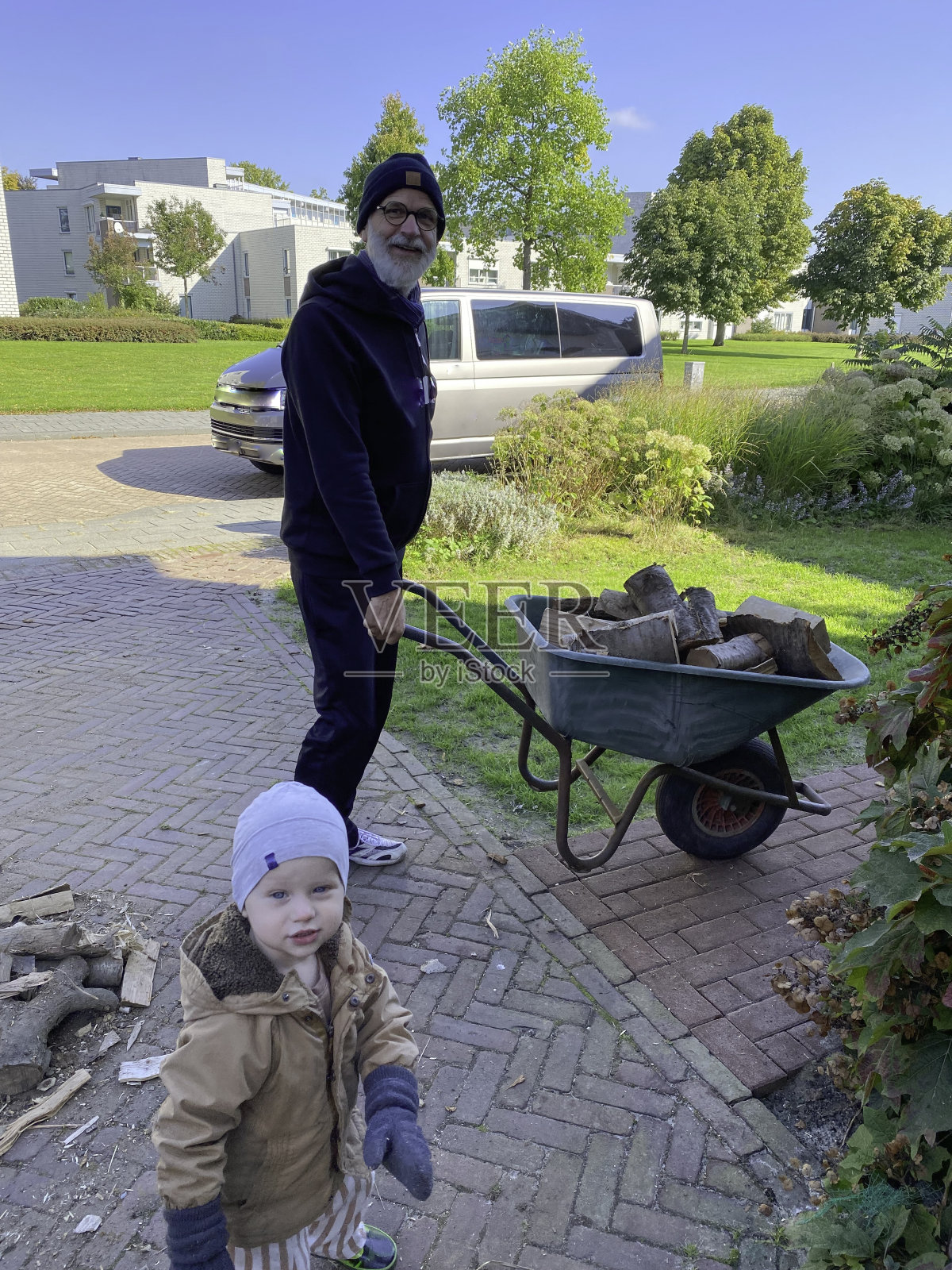 爷爷带着蹒跚学步的孙子堆柴火照片摄影图片