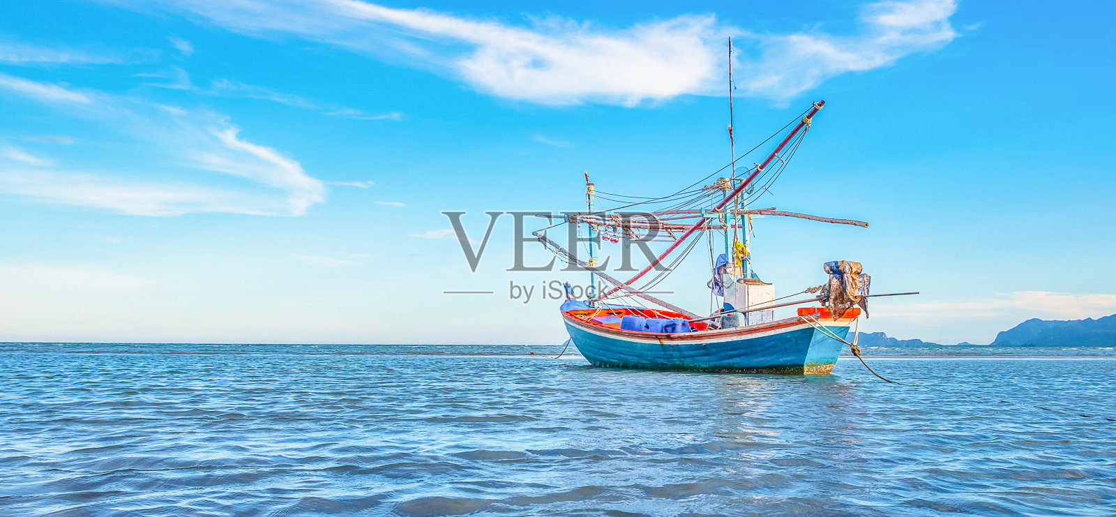 在美丽的碧海蓝天的清晨，一艘渔船停泊在海边。照片摄影图片