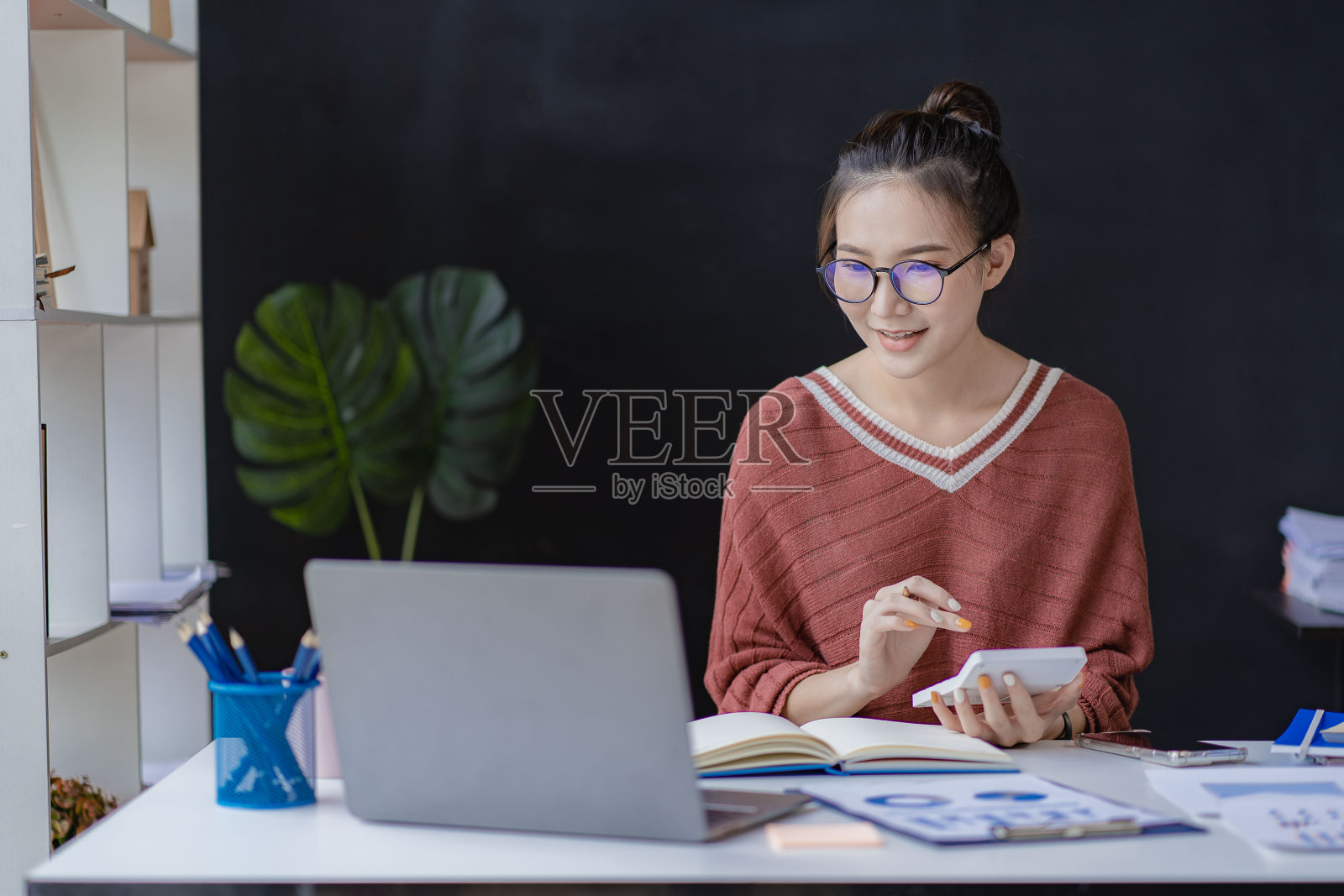 微笑成功的亚洲女性在她的办公桌上使用电脑和自由职业者的财务图表。电子商务在线营销理念照片摄影图片