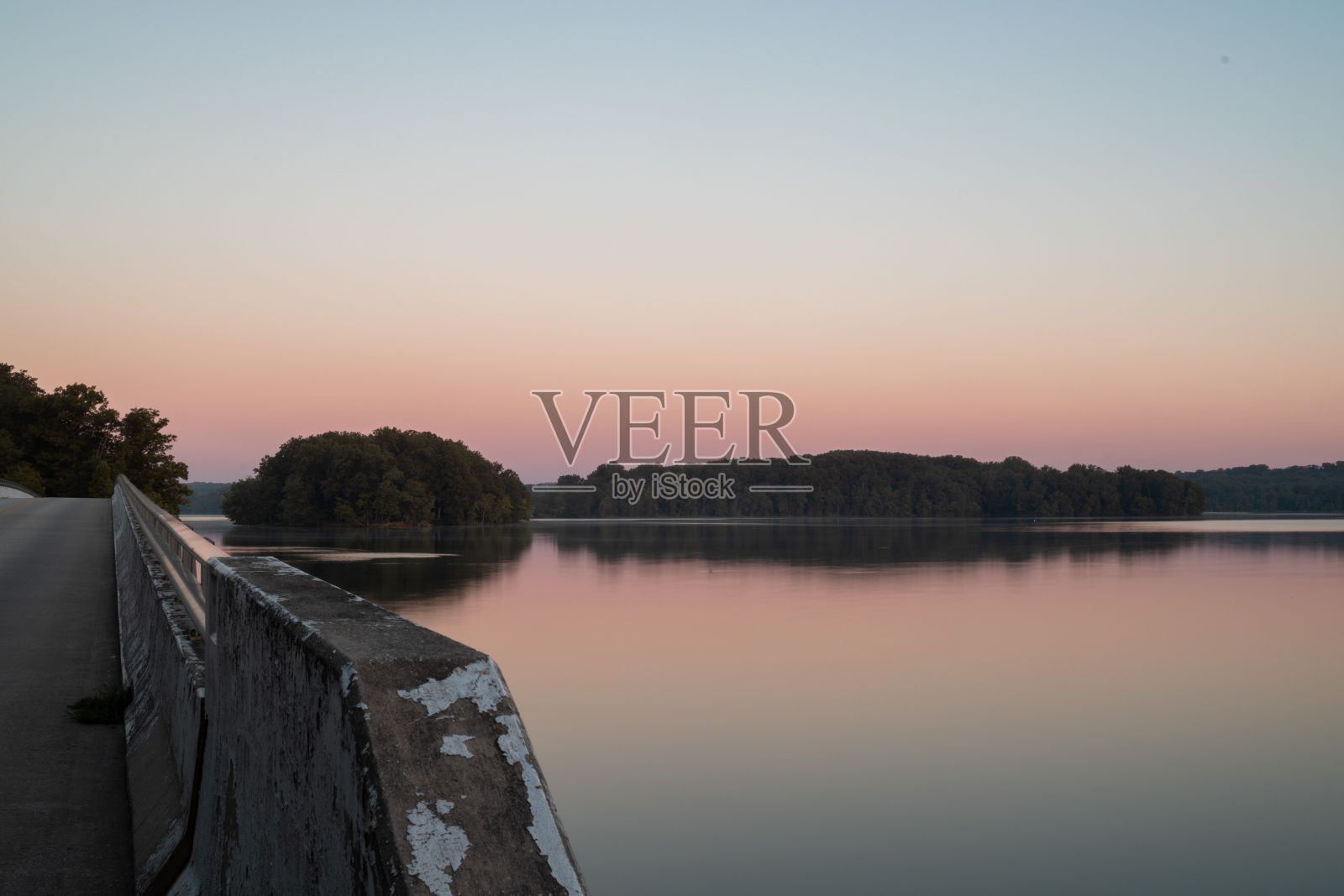 粉红色的日落天空下，美丽的湖与森林小山的背景照片摄影图片