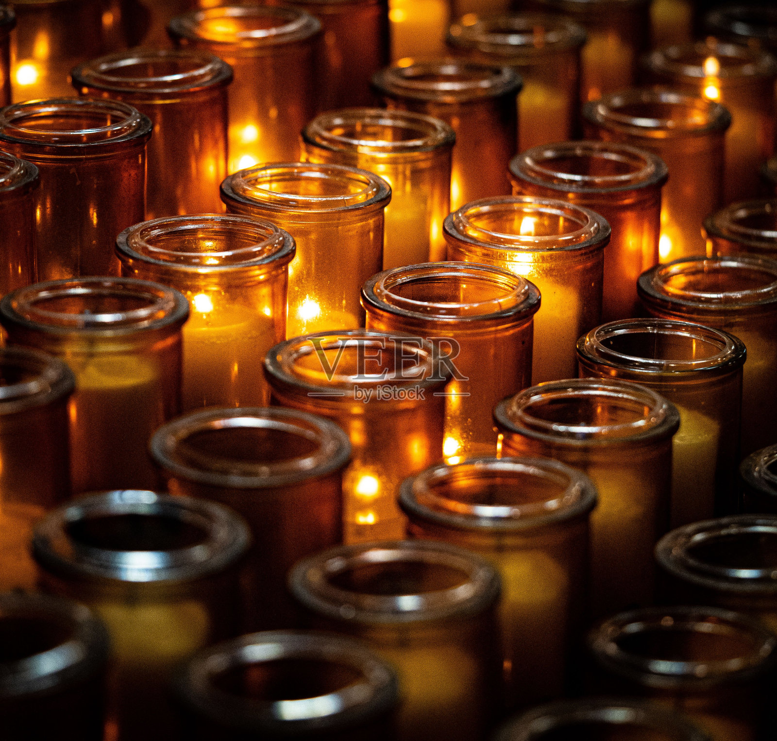 玻璃罐中一排排燃烧的蜡烛的特写照片摄影图片