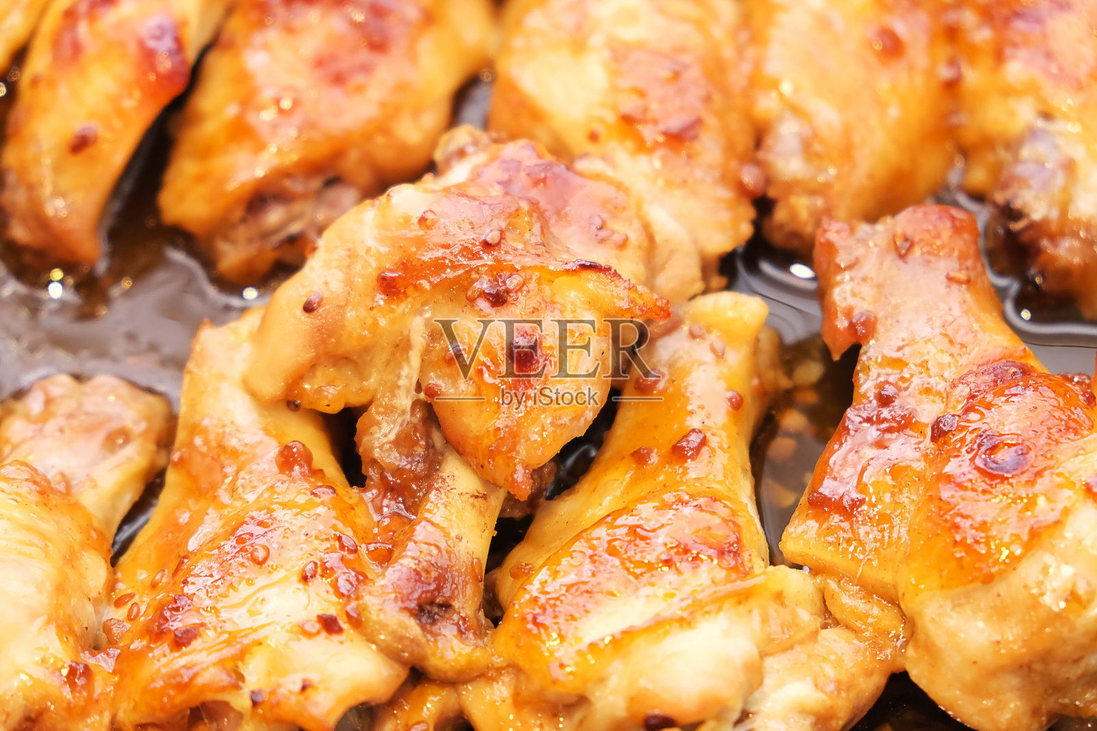 烤鸡翅部分与大蒜在煎锅近食物照片。刚出炉的烤家禽。自制的厨房。在家做饭。照片摄影图片