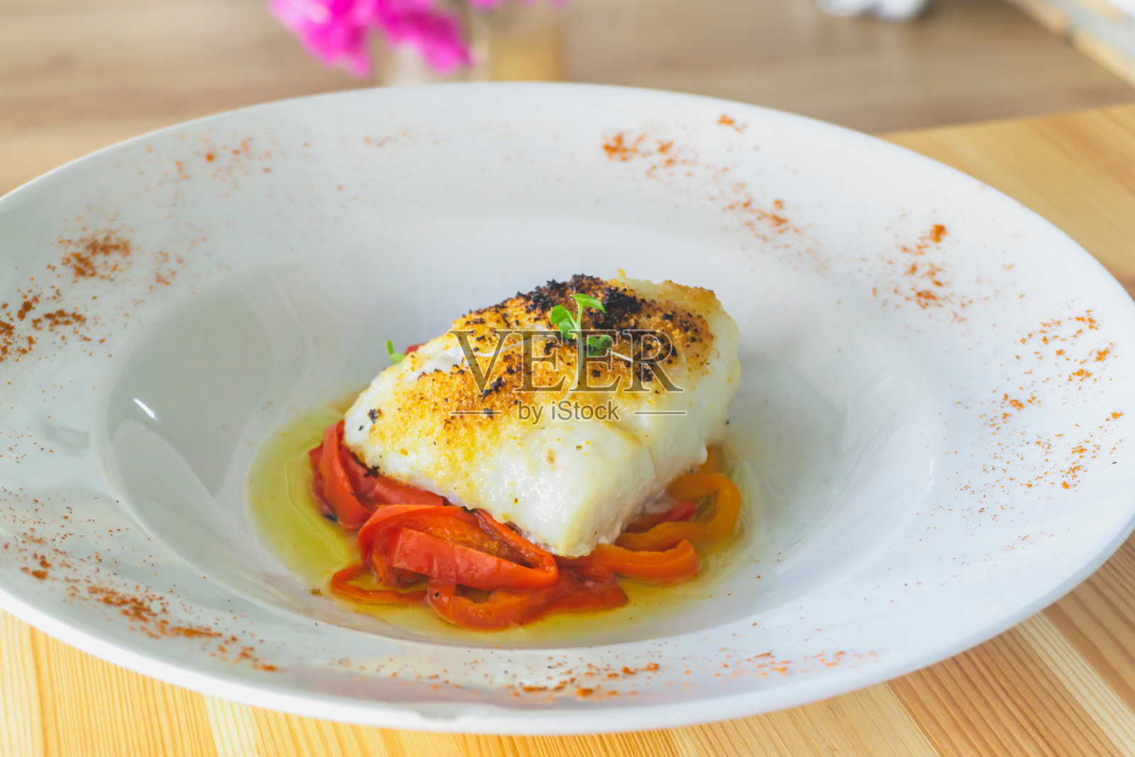 美味的烤鳕鱼配烤红辣椒放在木桌上。照片摄影图片