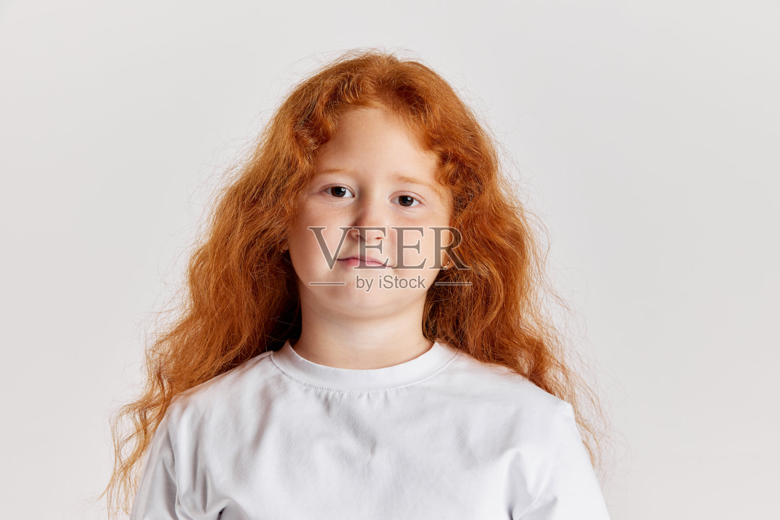 可爱的小女孩，长卷红色头发的孩子看着相机孤立在白色背景。观念儿童积极的情绪、美好的事物照片摄影图片