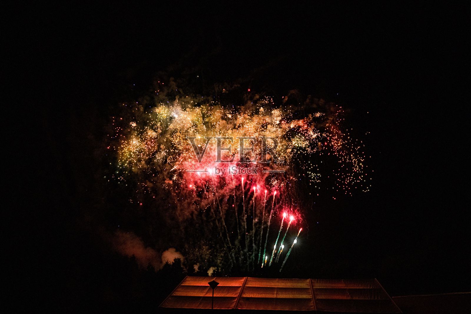 风景如画的红色烟花在漆黑的夜空上，掠过建筑物照片摄影图片