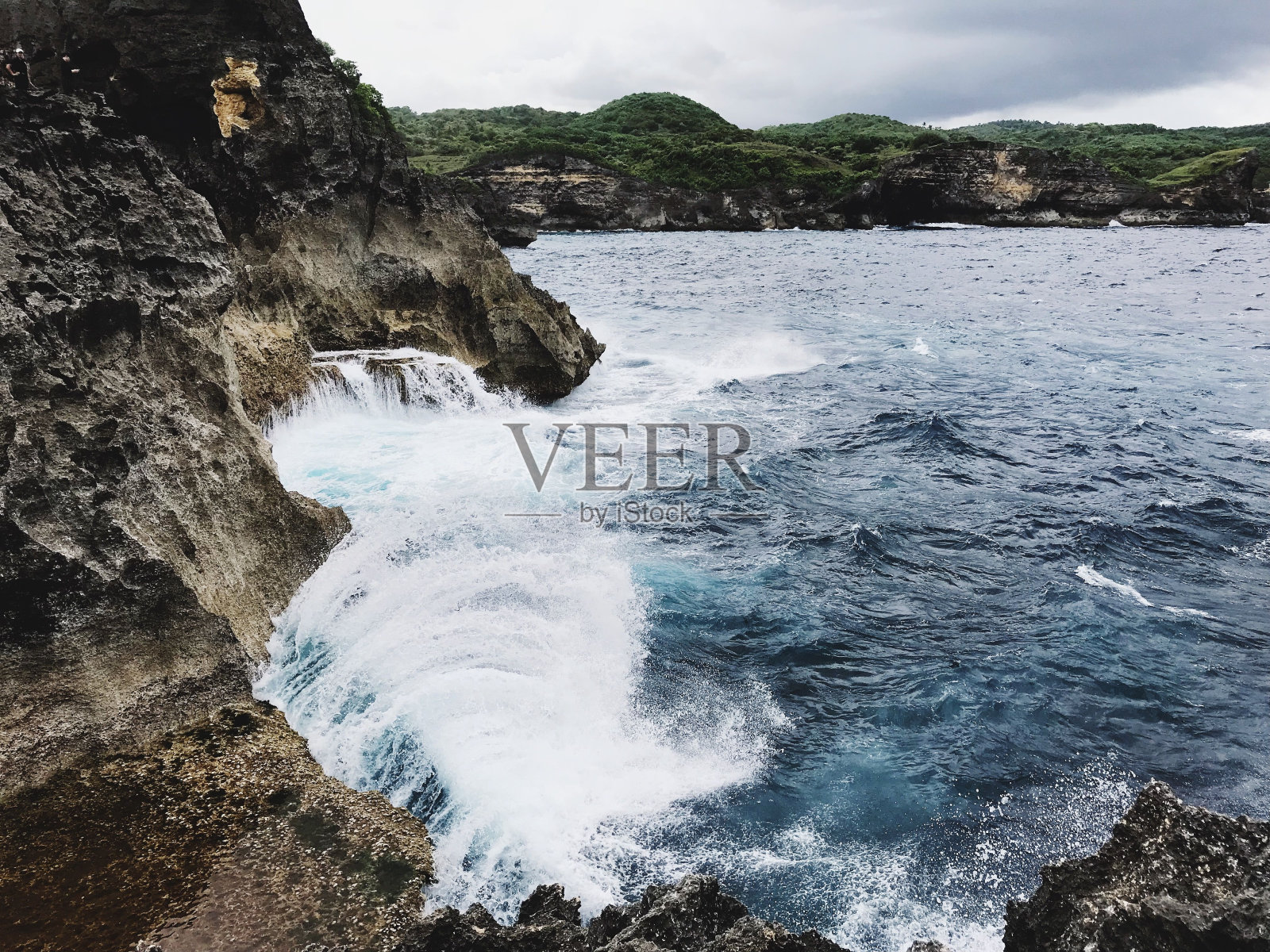 在比拉蓬岛，多云的天空下，海浪拍打着悬崖照片摄影图片