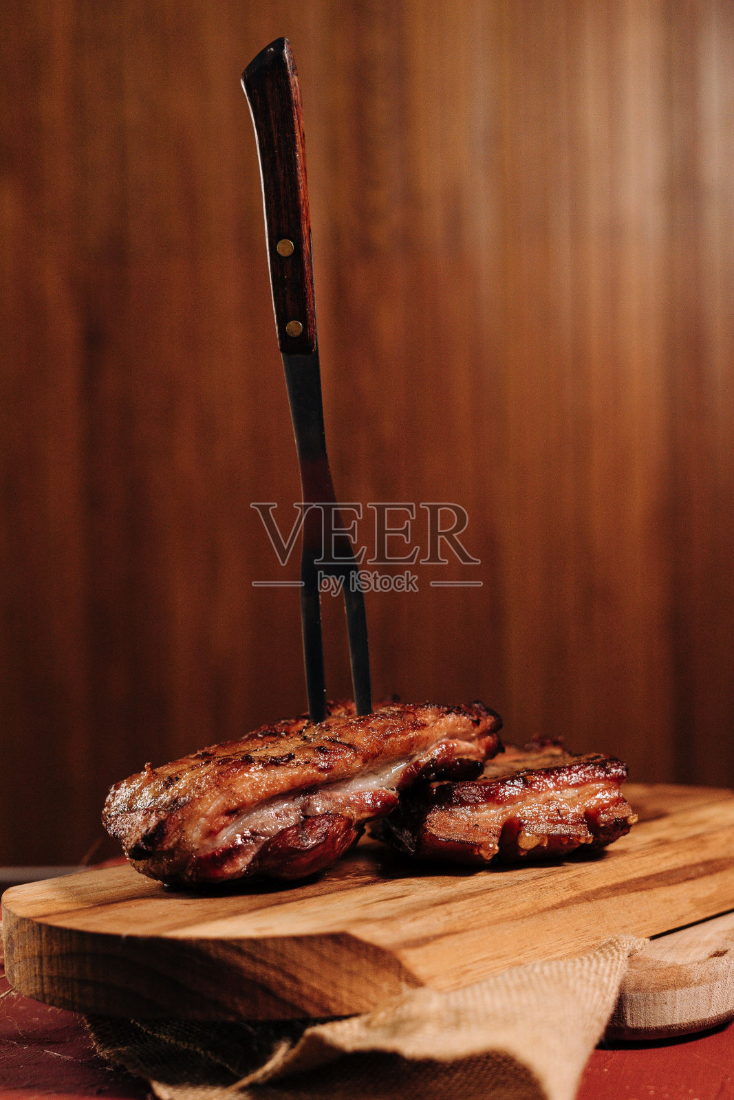 垂直的肉叉扎在木板上的熟牛排上照片摄影图片