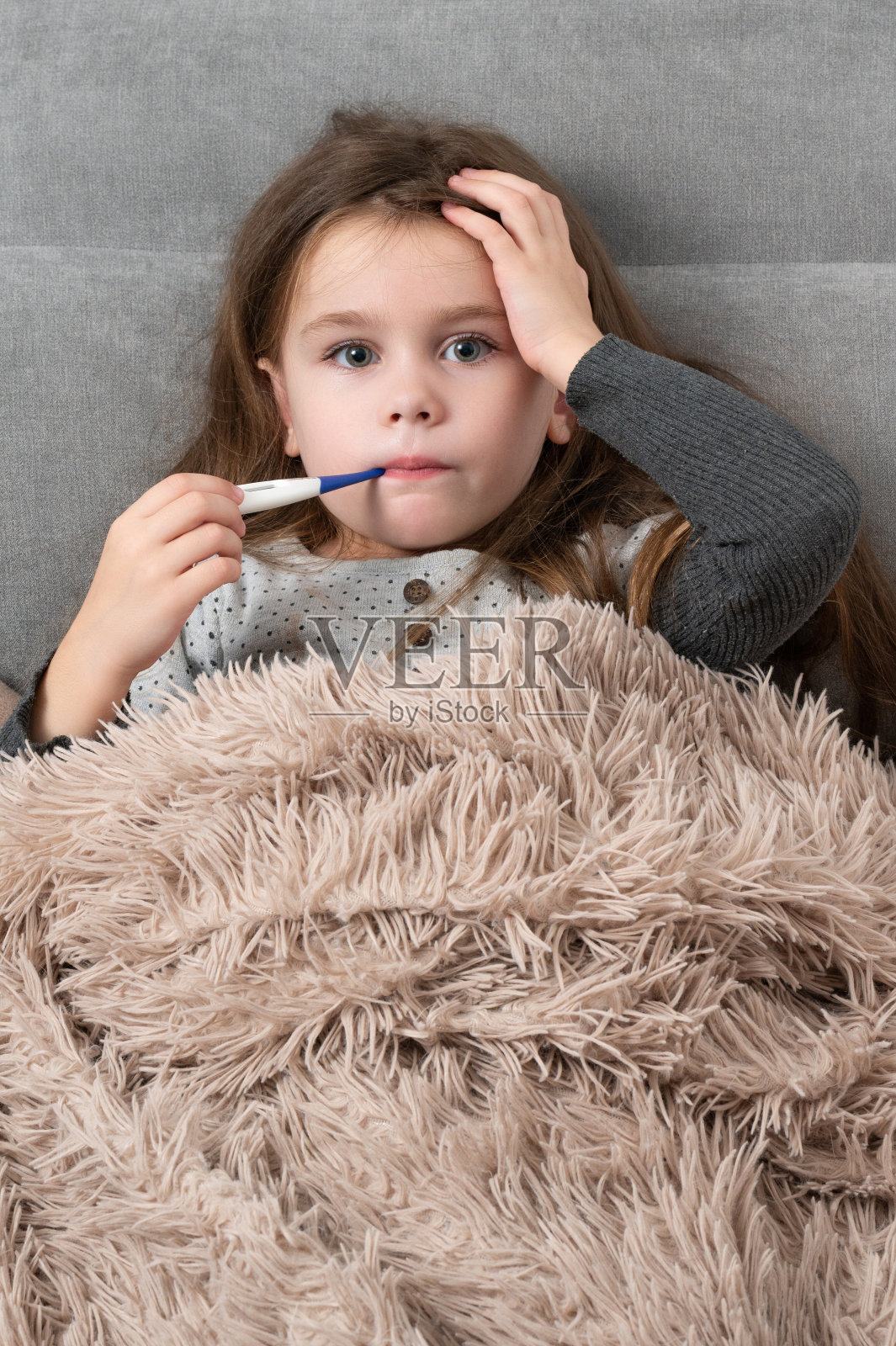 一个可爱的小女孩躺在床上生病了。照片摄影图片