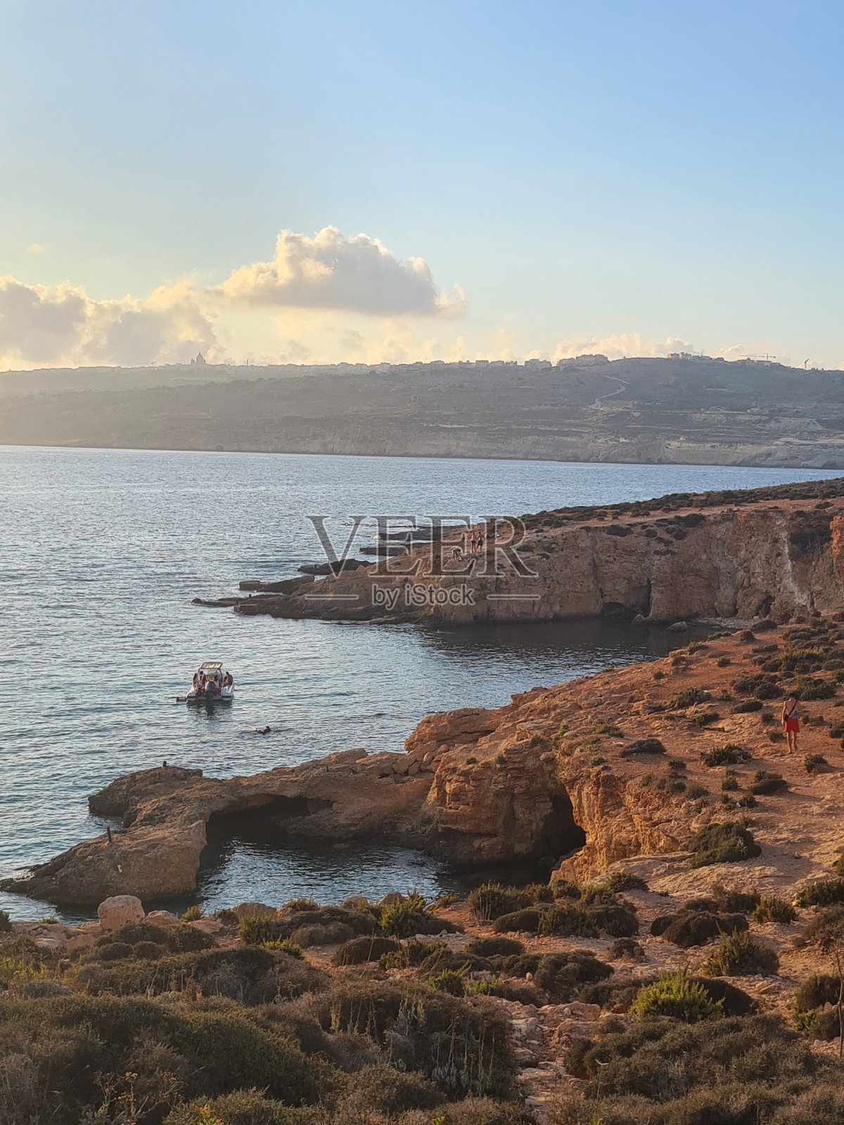 在美丽的夕阳下，海滩海岸上的一个小悬崖的垂直镜头照片摄影图片