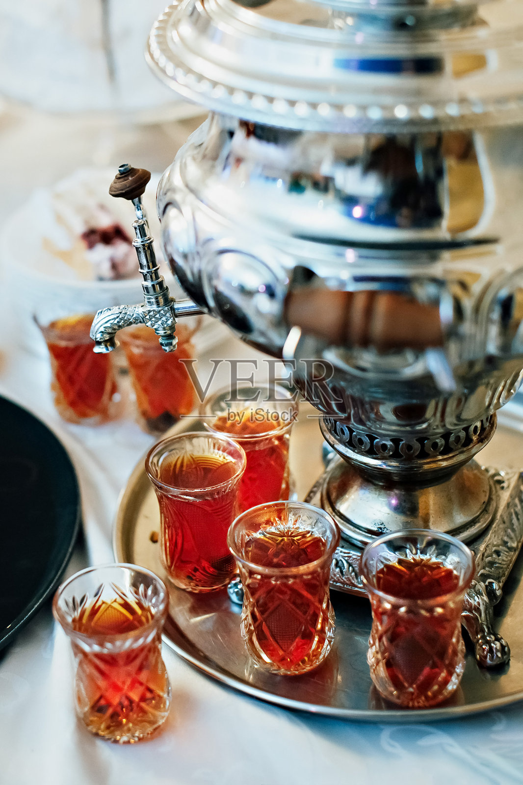 茶水用土耳其民族玻璃酒杯盛在托盘上，旁边是茶炊照片摄影图片