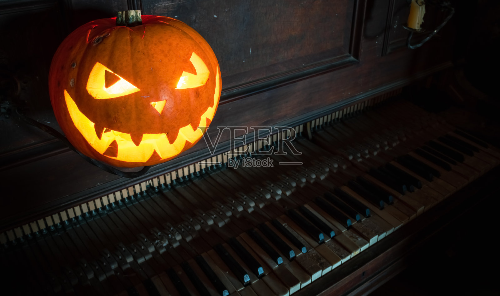万圣节南瓜灯，里面发光的是吓人的脸。装饰。旧钢琴。哥特式的概念。照片摄影图片