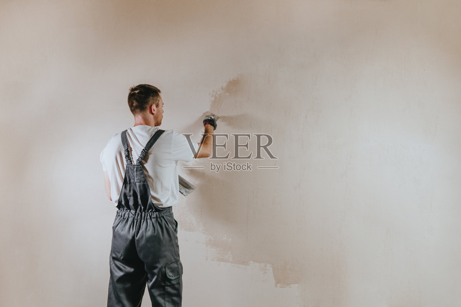 穿着工作服的建筑工人正在室内粉刷墙壁照片摄影图片