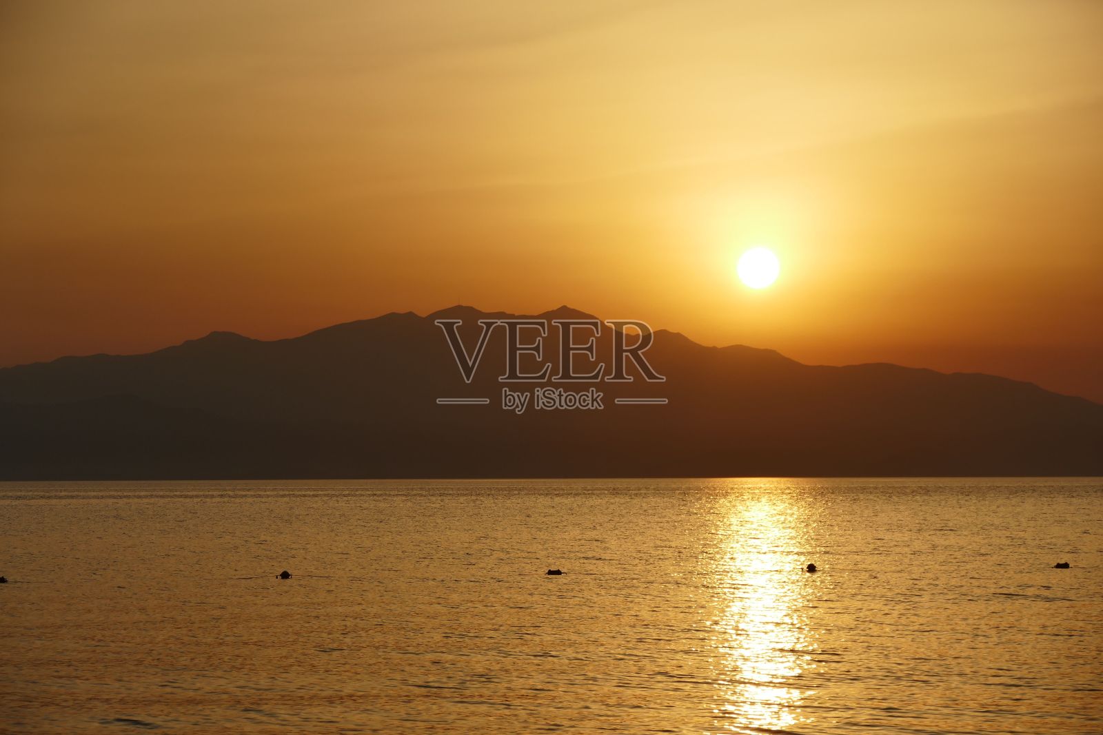 日落时山脉横跨大海的剪影照片摄影图片