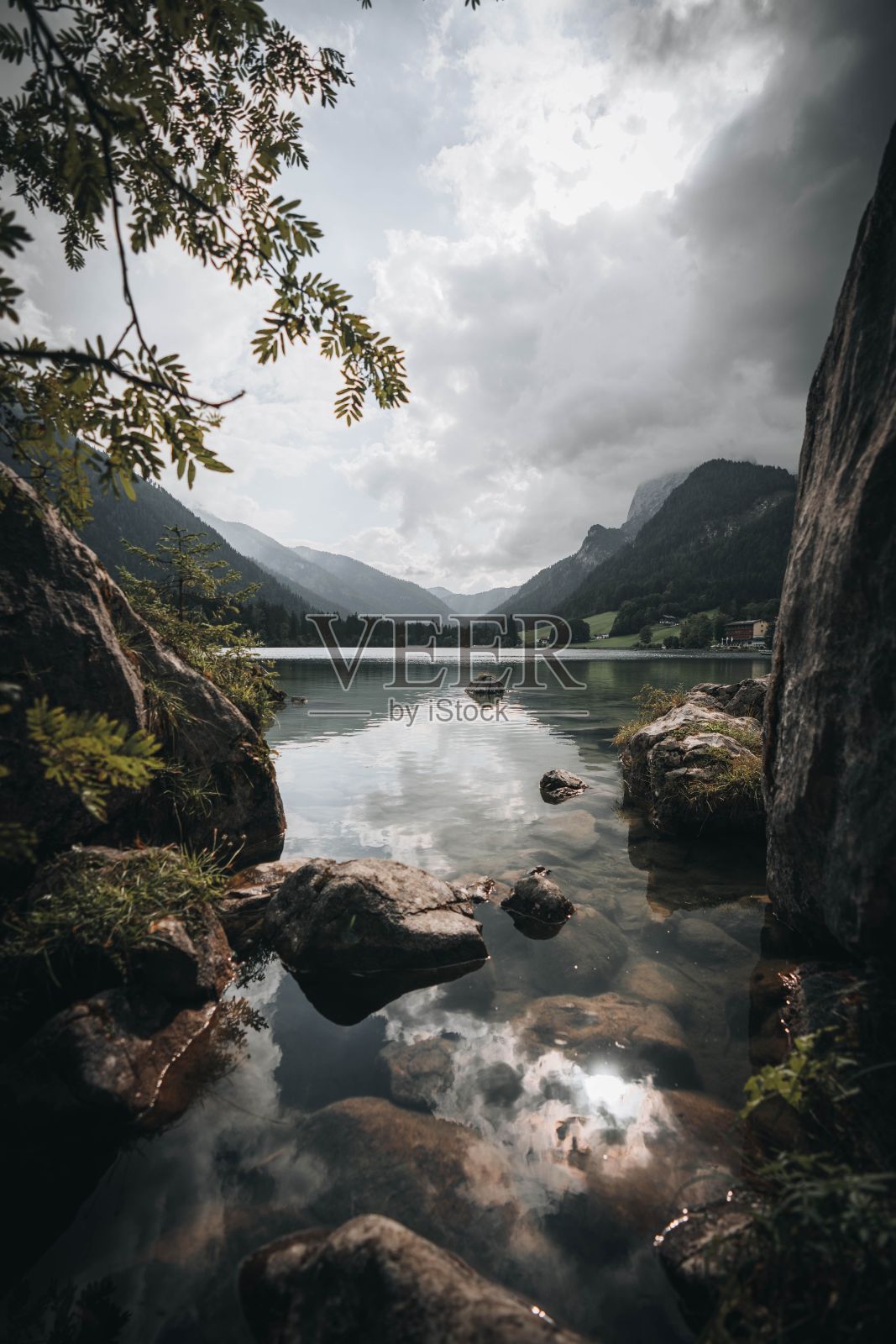 德国群山背景下，阴天下岩石嶙峋的Hintersee湖的垂直拍摄照片摄影图片