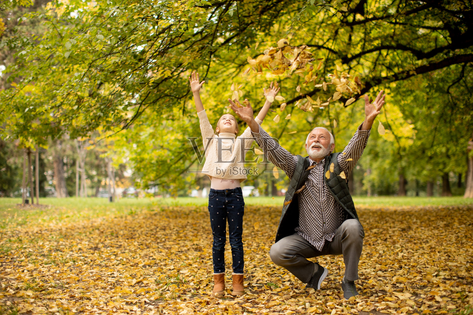 秋天的一天，爷爷和孙女在公园里玩照片摄影图片