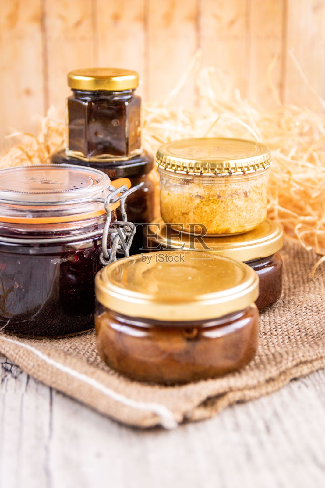 垂直拍摄自制烹饪产品的罐子，如果酱和酱汁，靠近装饰稻草照片摄影图片