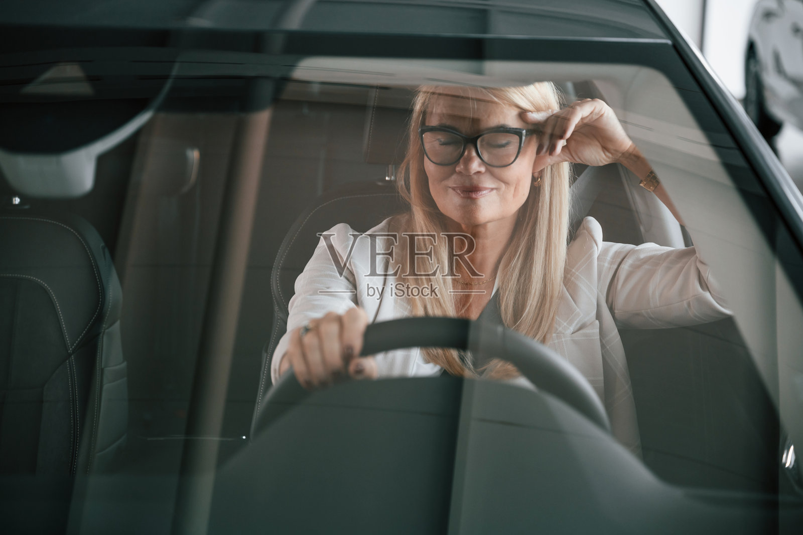 前视图。穿白色正装的女人在汽车经销店里照片摄影图片