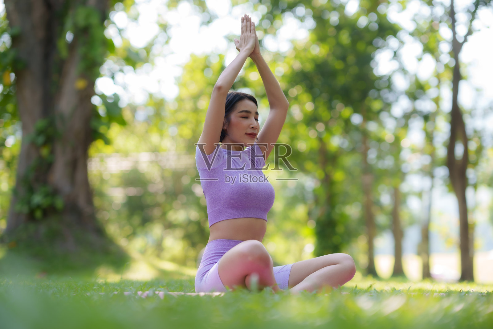 在公园里做瑜伽。年轻的亚洲女子在公园里练习瑜伽姿势。照片摄影图片