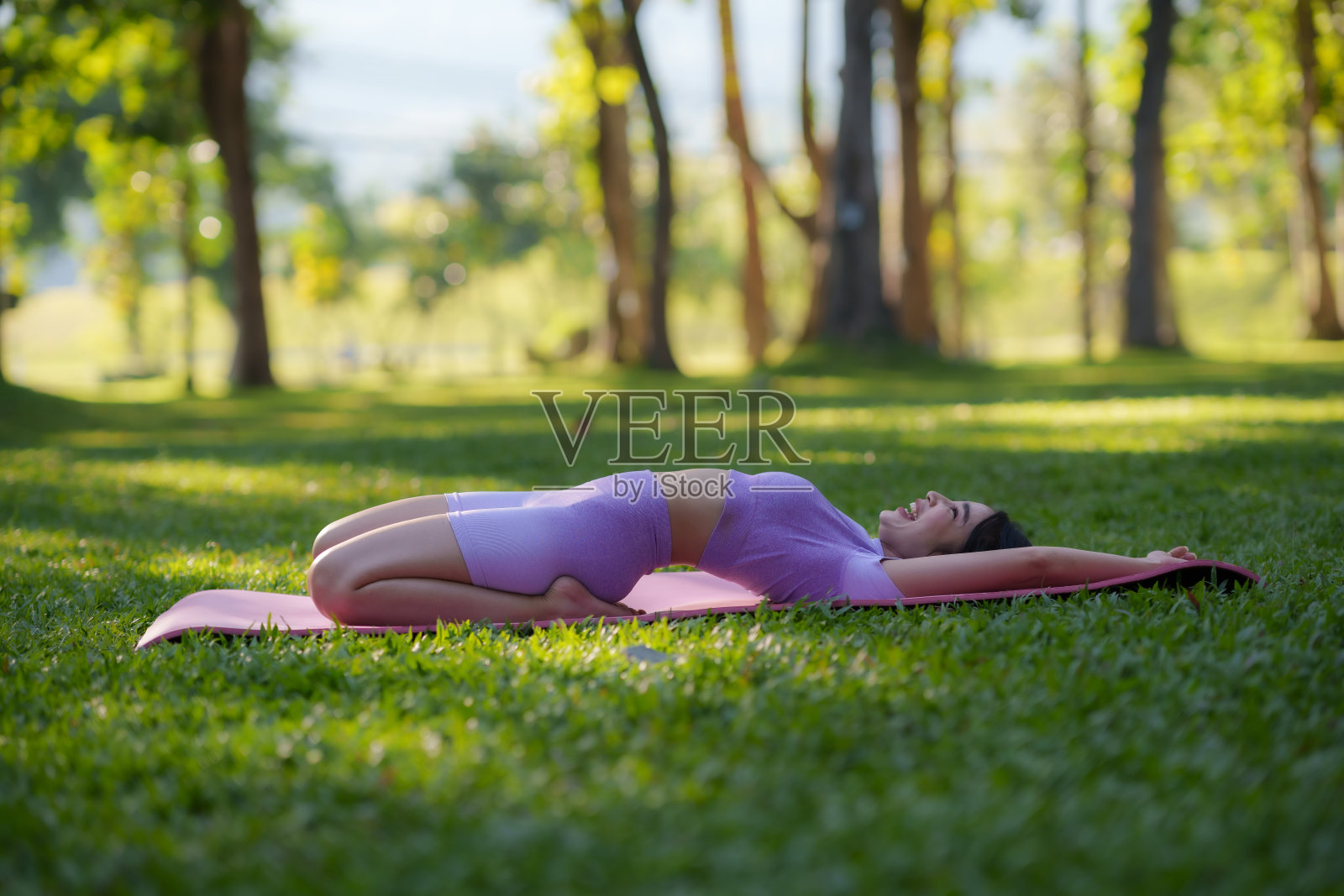 在公园里做瑜伽。年轻的亚洲女子在公园里练习瑜伽姿势。照片摄影图片