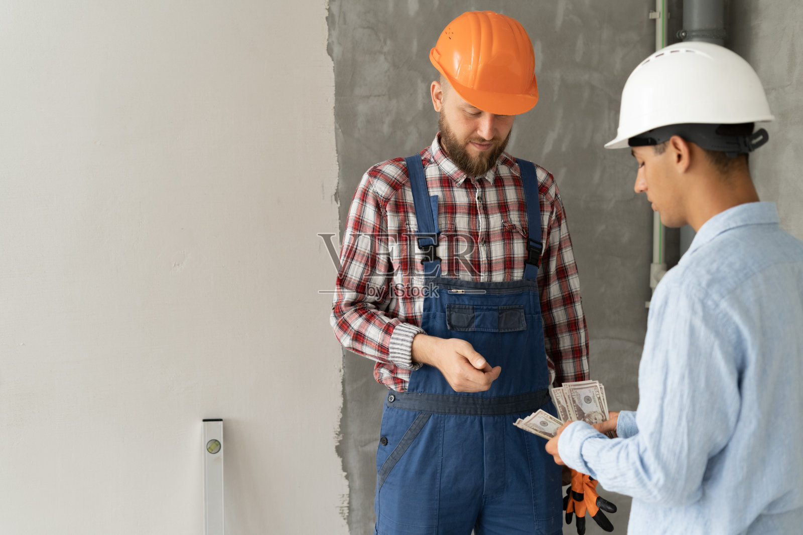 发薪日。非法建筑工人收受客户的钱，土木工程师在建筑工地给工人钱。支付房屋维修协议照片摄影图片