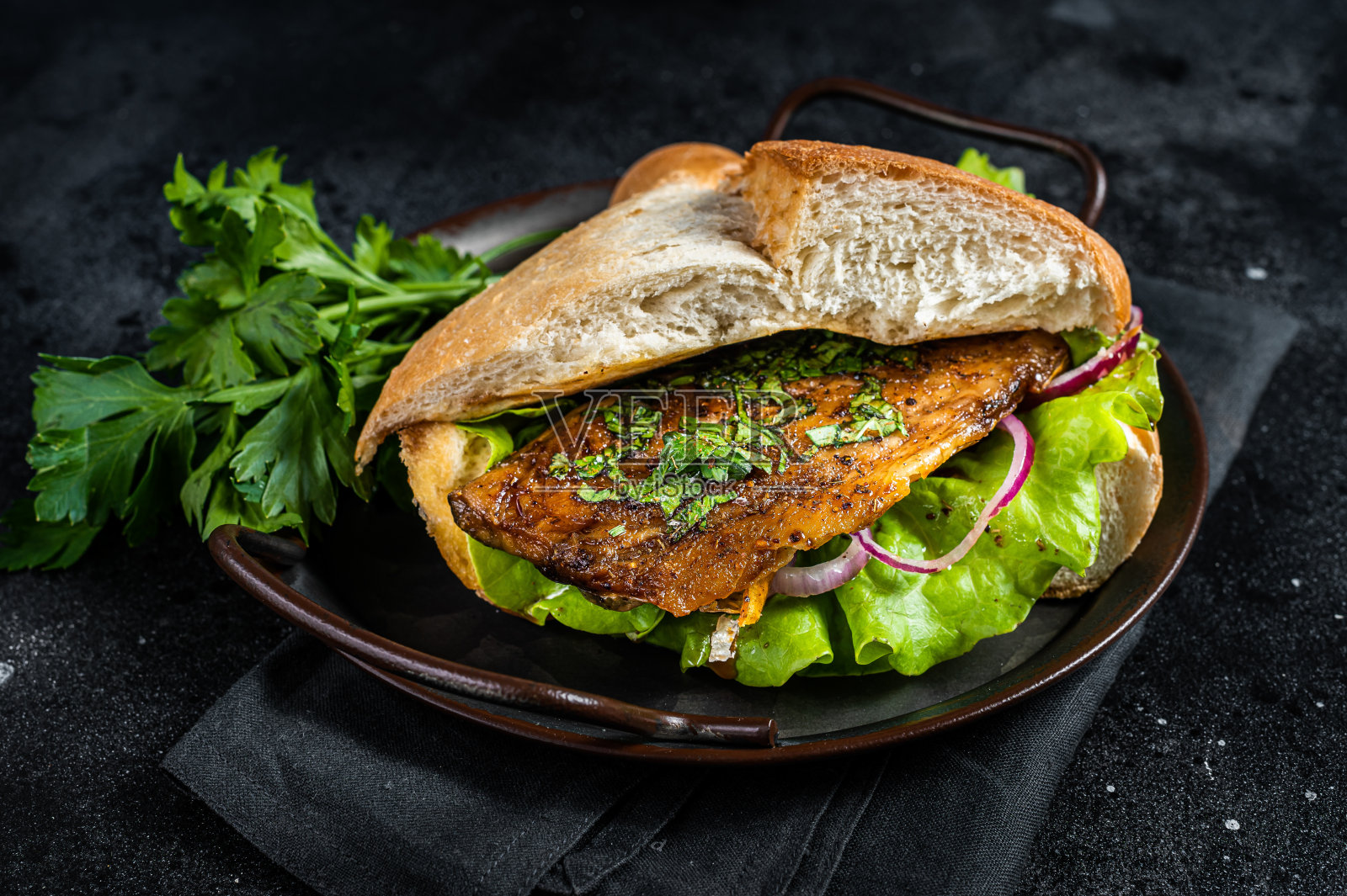 用烤鲭鱼片、番茄、洋葱和生菜做三明治。黑色背景。俯视图照片摄影图片