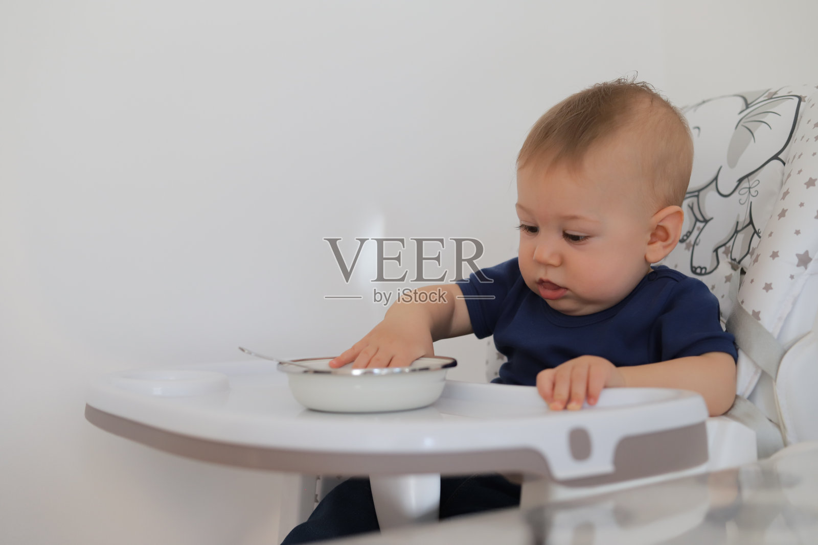 婴儿坐在喂食器里等待午餐。照片摄影图片