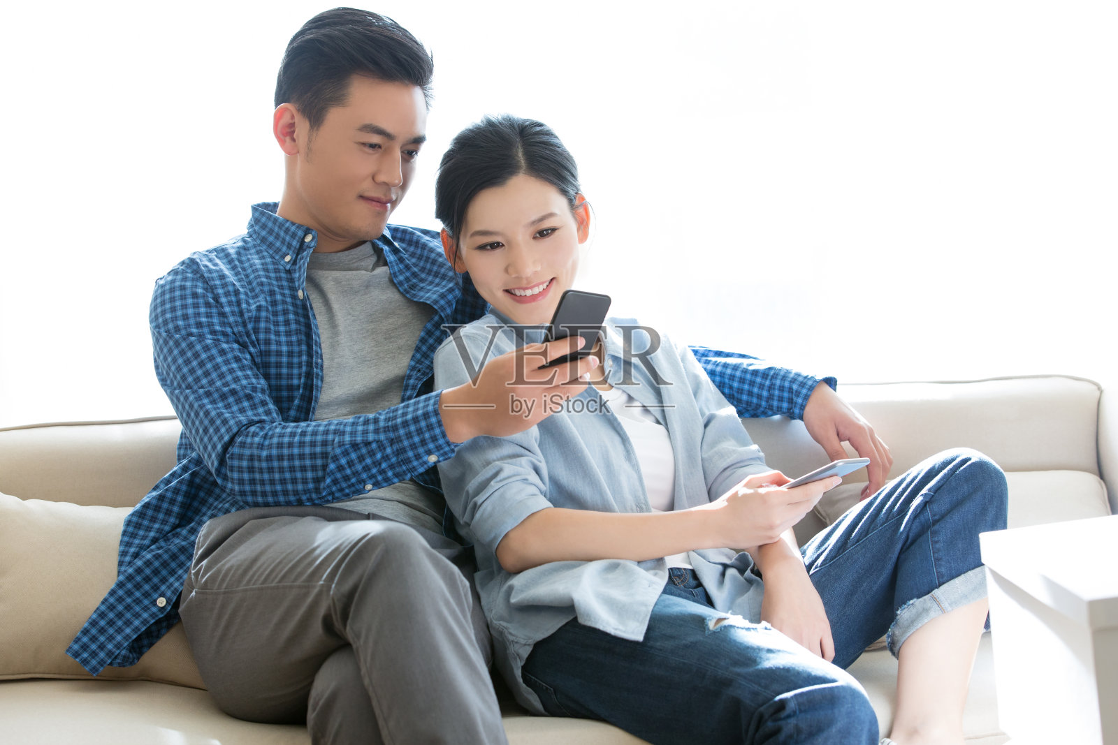 年轻夫妇在搬家时懒洋洋地躺在沙发上使用他们的智能手机——库存照片照片摄影图片