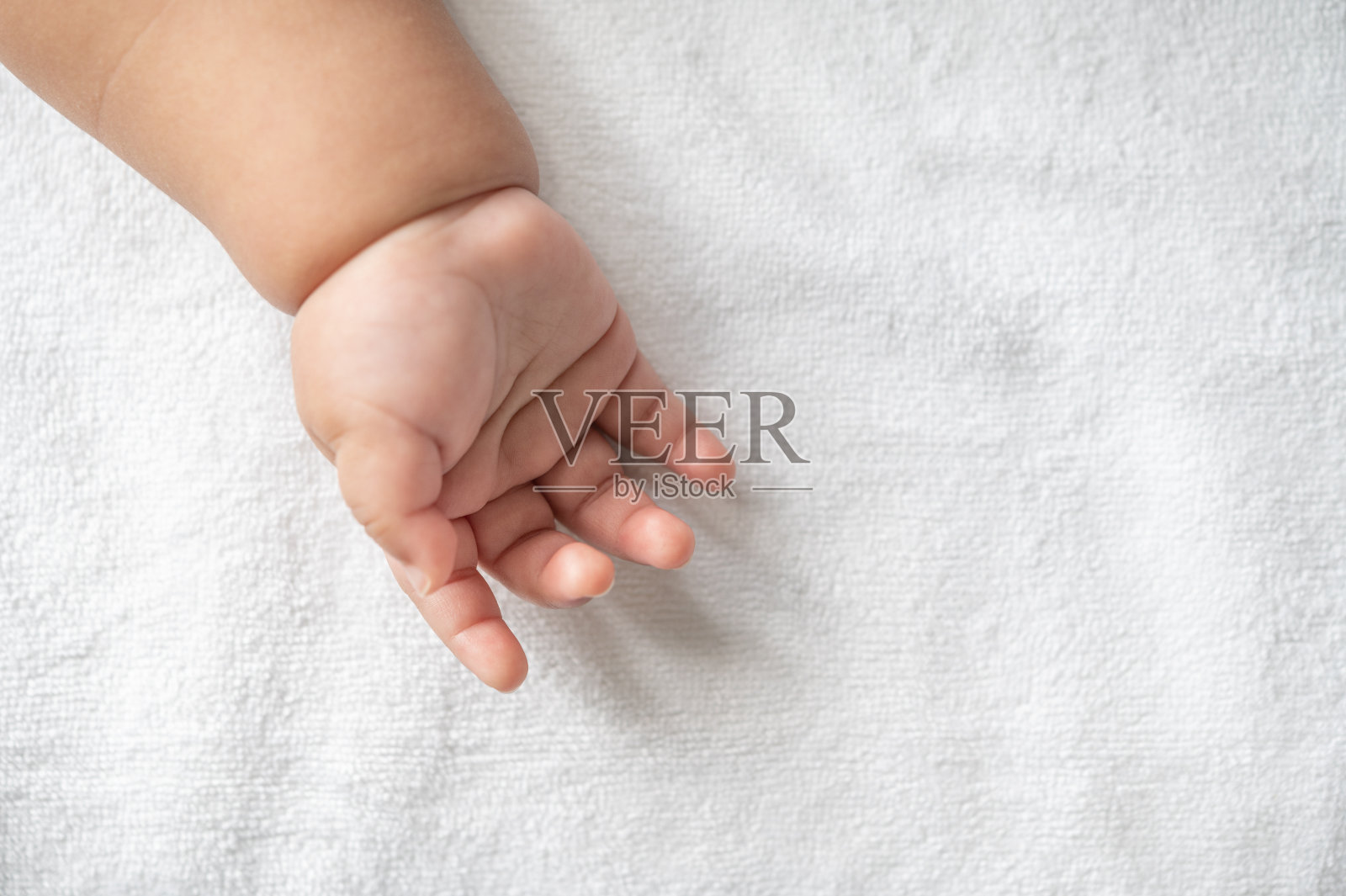 刚出生的婴儿手在白色的床上照片摄影图片