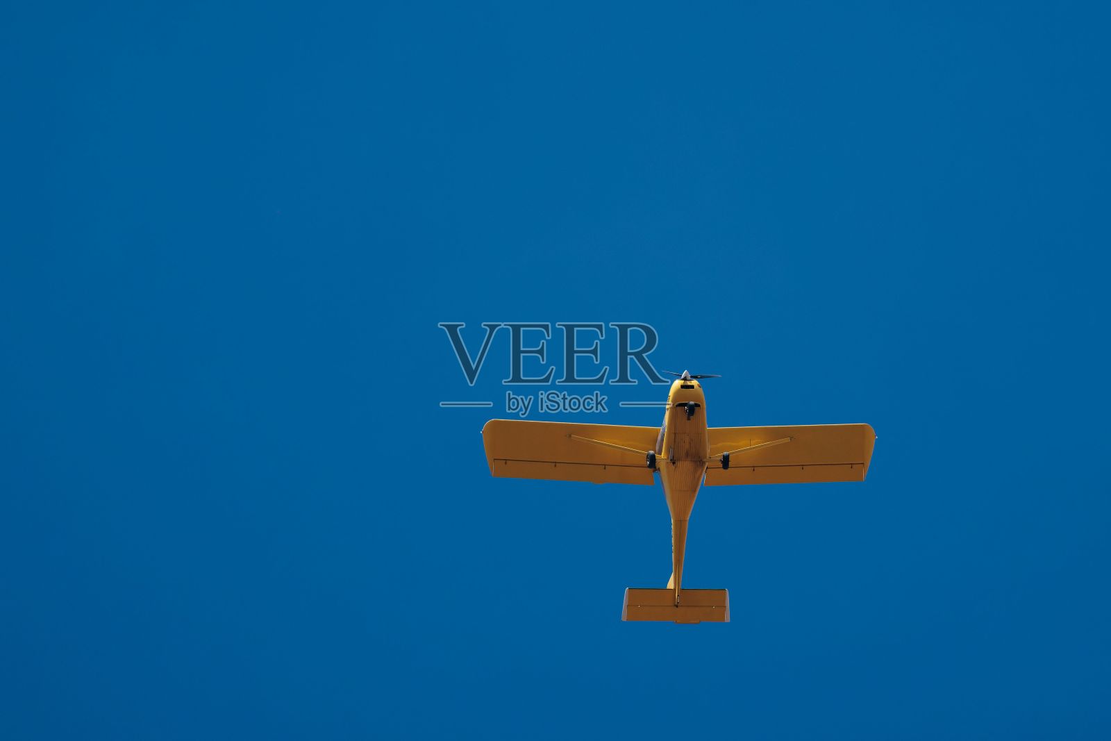 一架黄色飞机在蓝天中低角飞行照片摄影图片