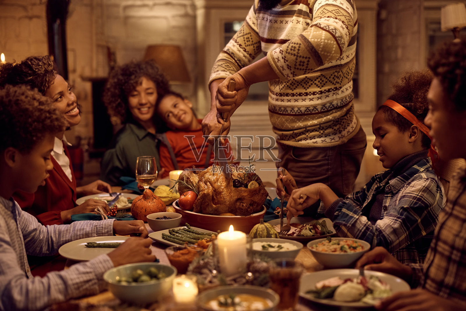 一个非裔美国人在感恩节家庭聚餐时切火鸡肉的特写镜头。照片摄影图片