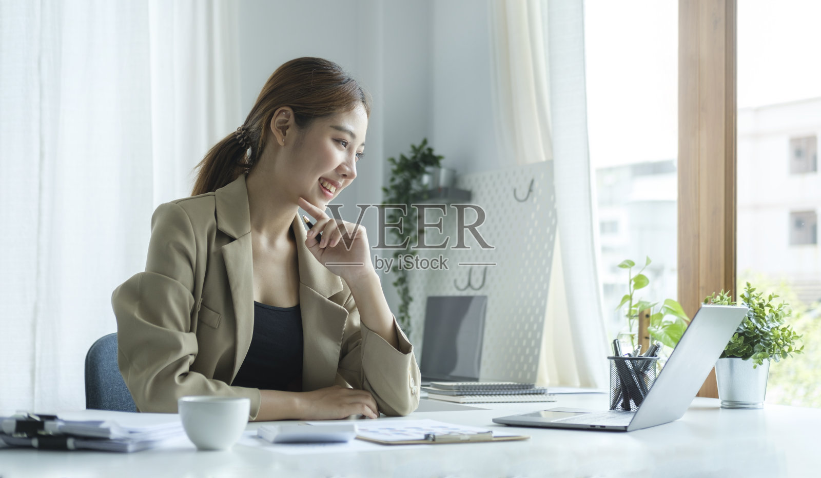 一位女商人在现代化的办公室里用笔记本电脑做新项目。照片摄影图片