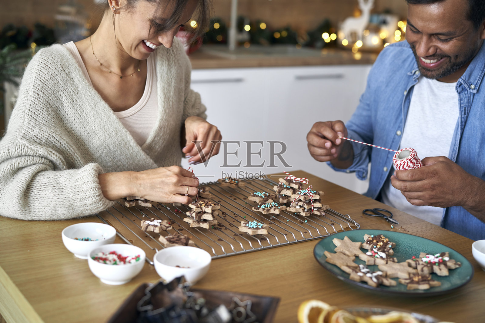 圣诞节期间，一对夫妇在家里装饰甜蜜的饼干照片摄影图片