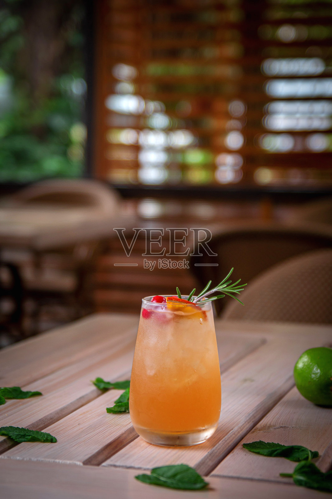 清新的杜松子酒鸡尾酒配橙汁，新鲜的蔓越莓和迷迭香配冰块，在夏日的餐厅露台上。照片摄影图片