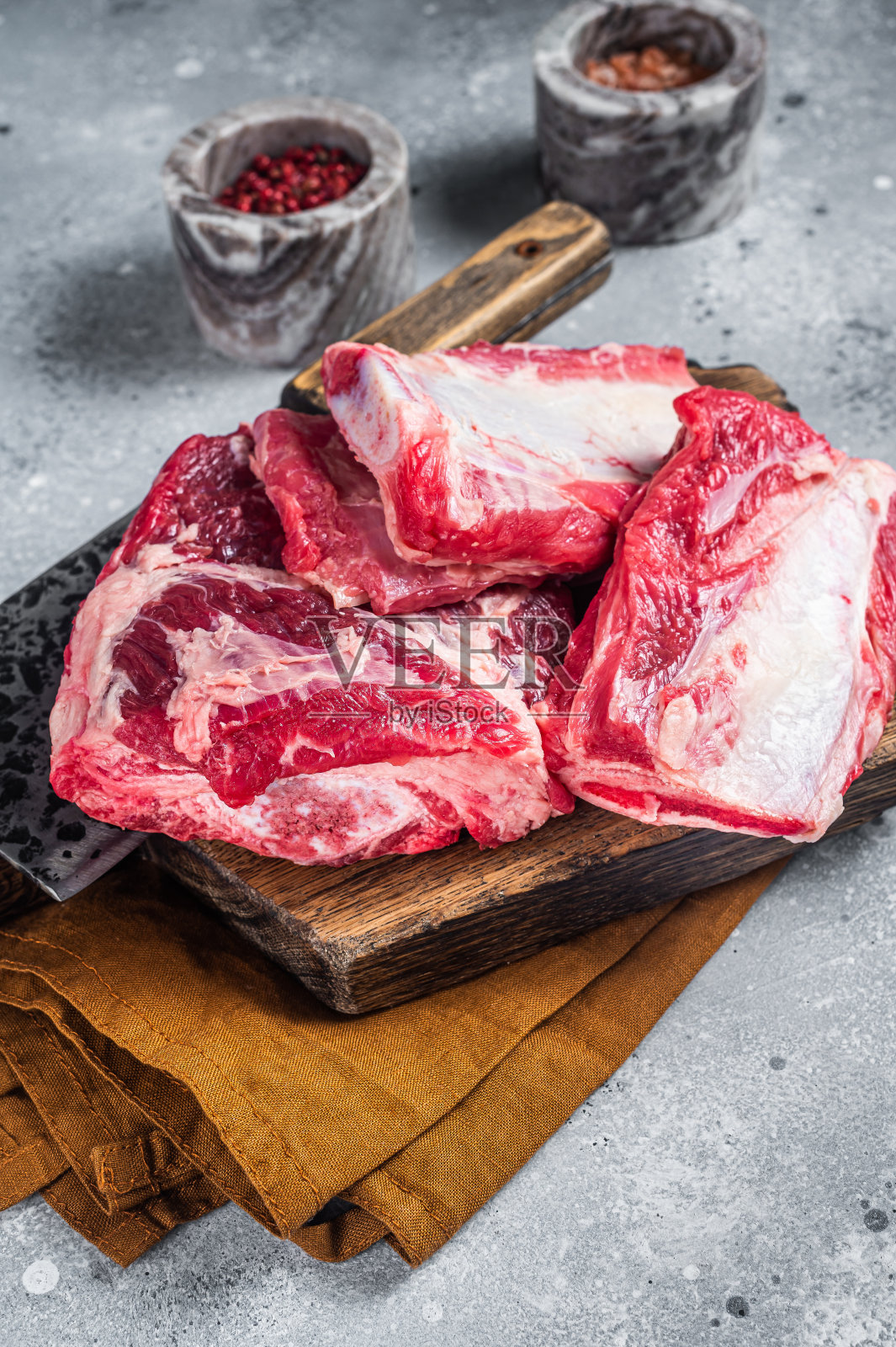 牛肉小牛肉排骨，生肉放在木砧板上。灰色的背景。俯视图照片摄影图片