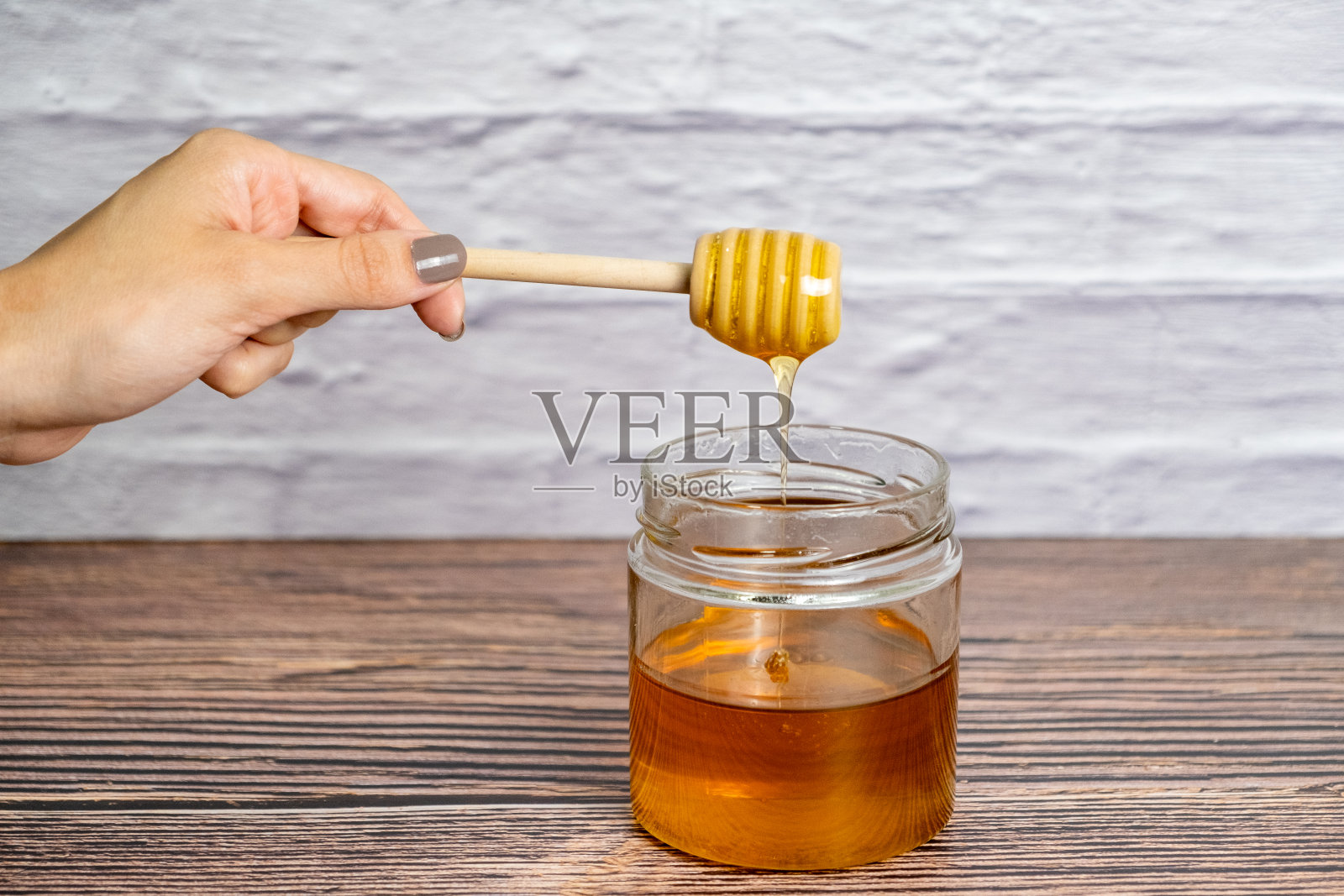 蜂蜜毛毛雨。蜂蜜罐和木棍孤立的白砖墙照片摄影图片
