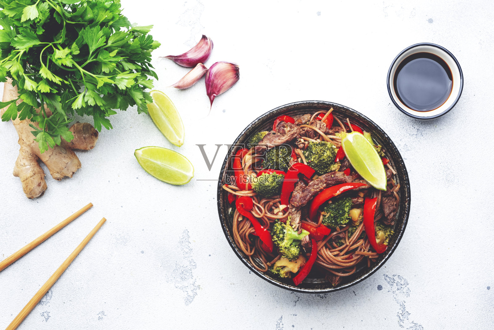 在白色的桌子背景，俯视图，炒面与蔬菜和牛肉，辣椒粉和西兰花芝麻在碗里照片摄影图片