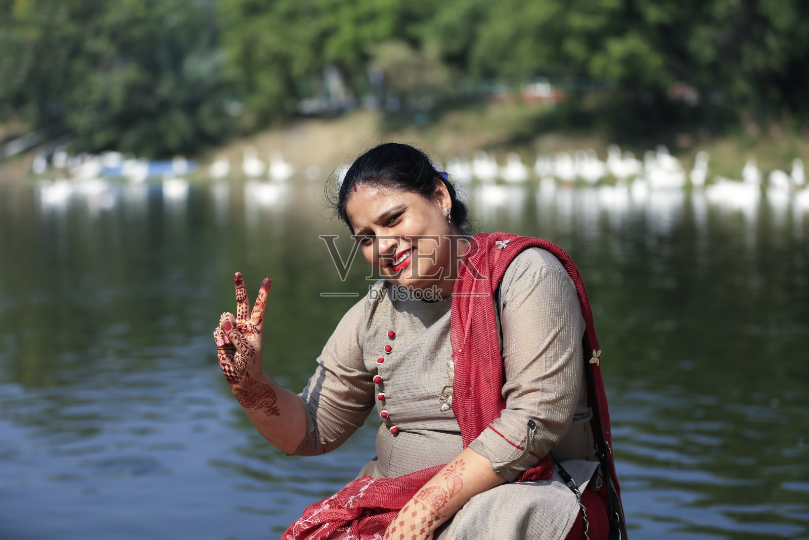 漂亮的女人在湖边的肖像和胜利的标志照片摄影图片