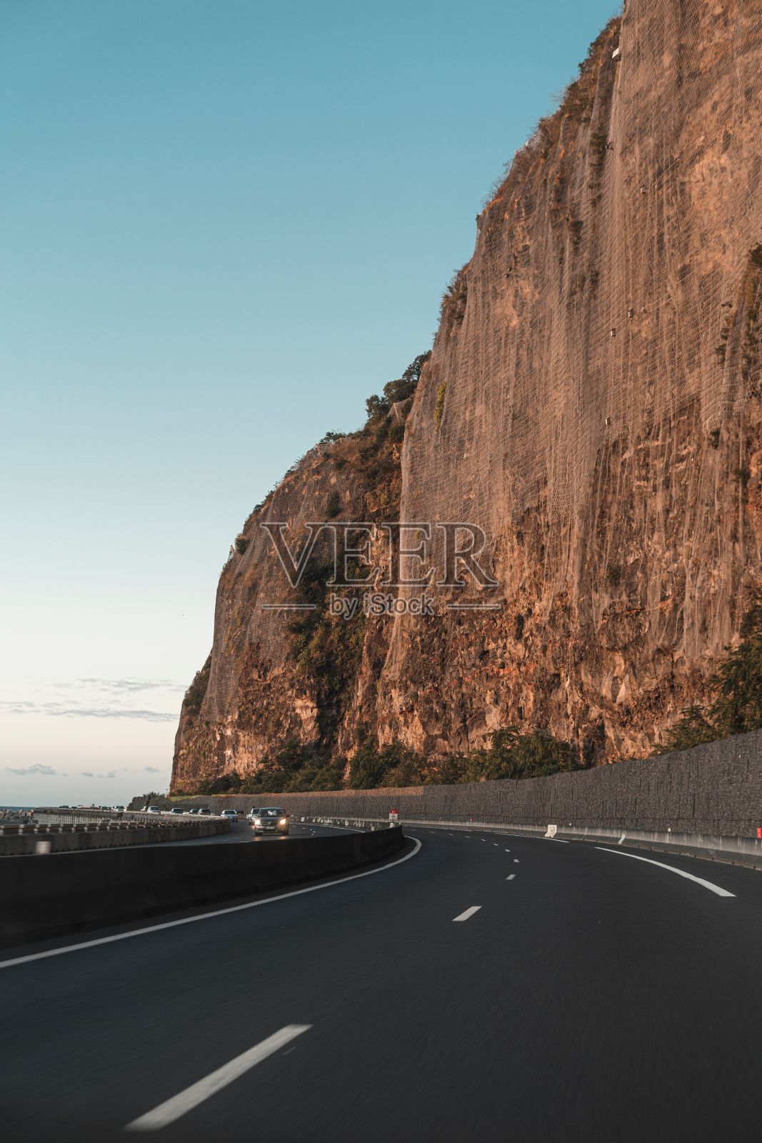在湛蓝的天空下，一条空旷的道路被巨大的岩石峭壁俯瞰照片摄影图片