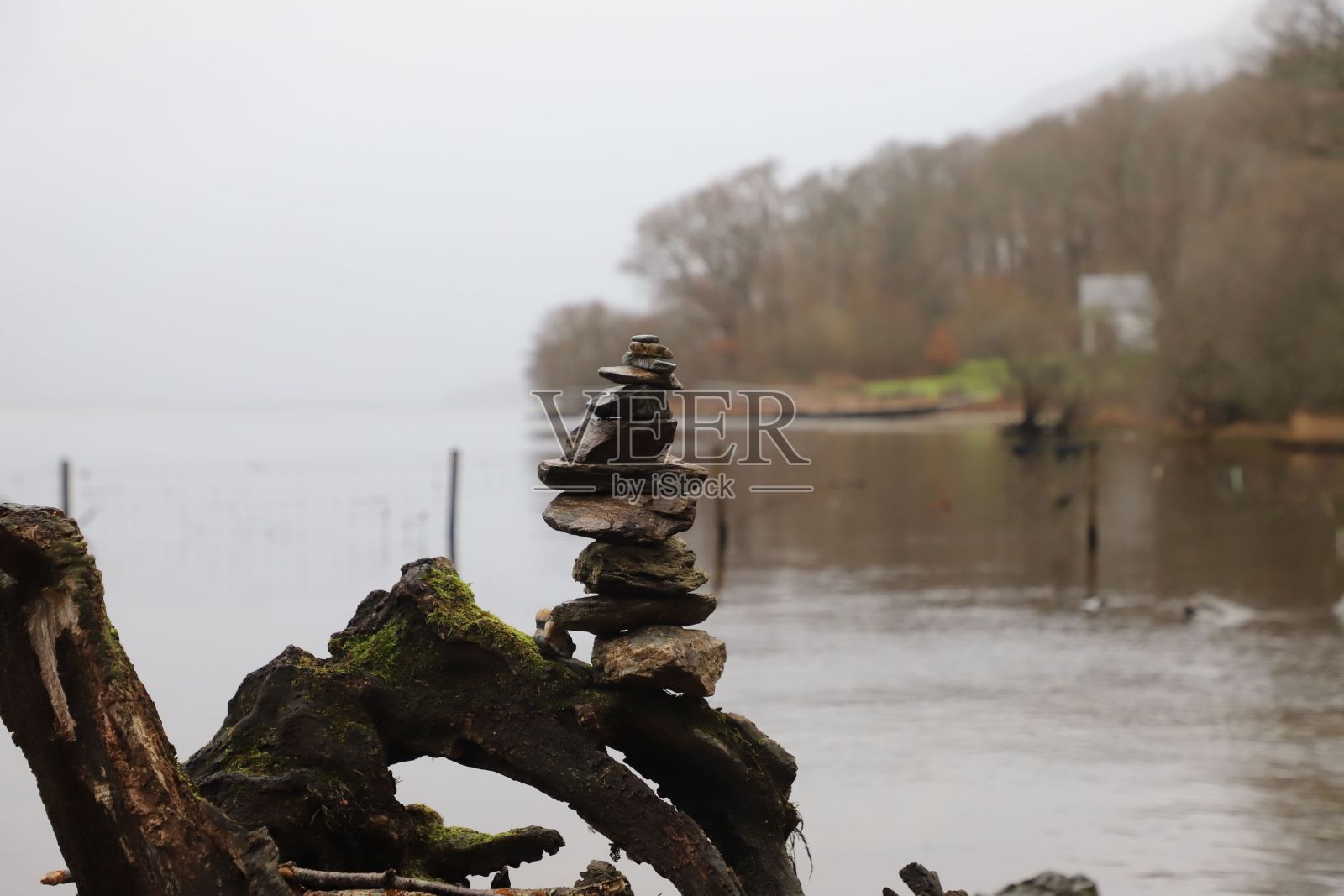 在一个阴天，一堆石头相互平衡，背景是湖和树照片摄影图片