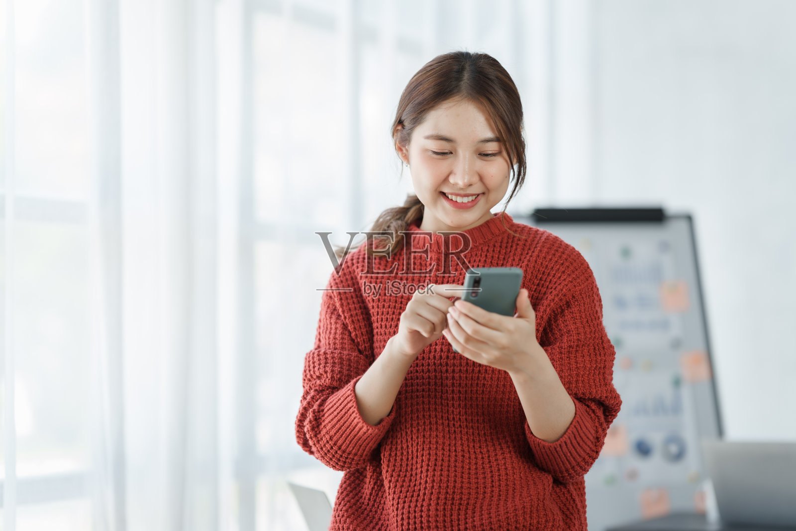 自信的亚洲女白领自由职业者在办公室工作，穿着红色毛衣，泰国人。照片摄影图片