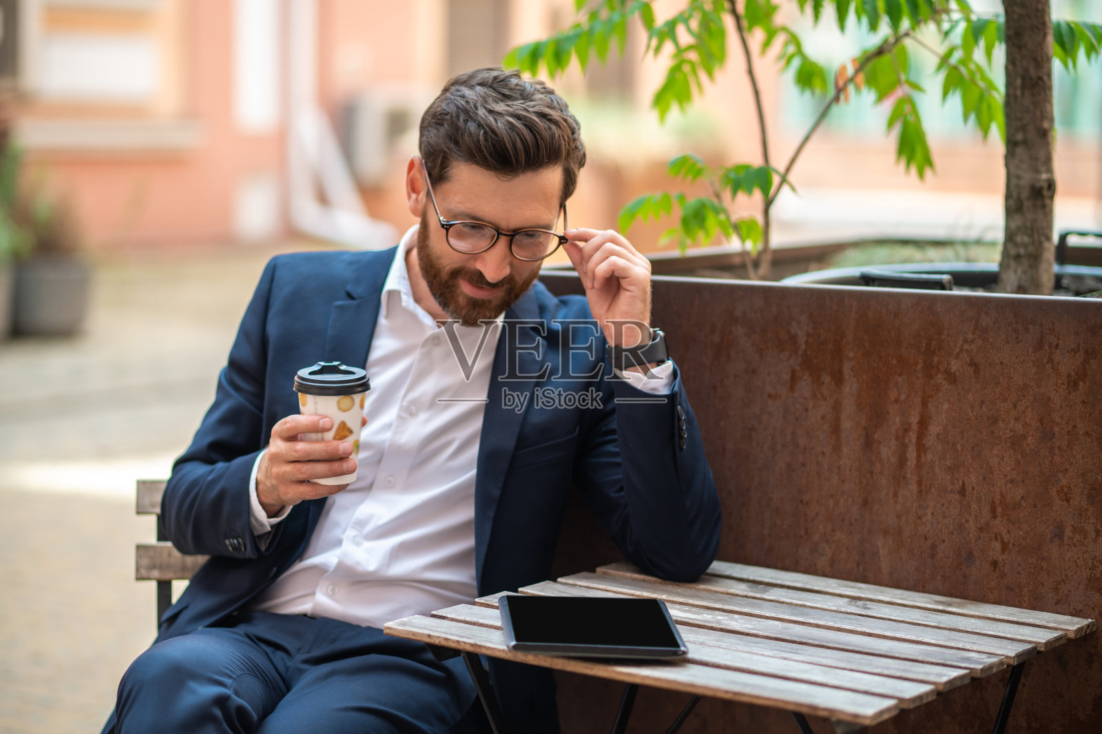 一个穿着西装的年轻人坐在街边的咖啡馆里喝咖啡照片摄影图片