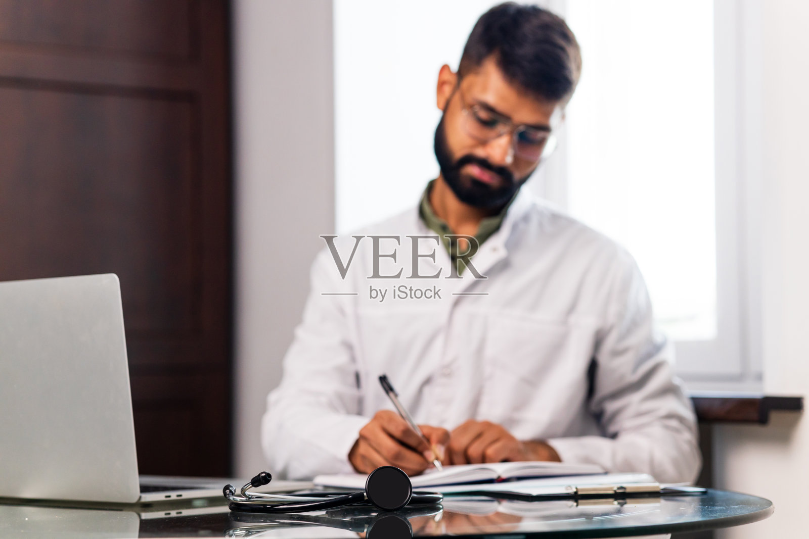 穿着白大褂的印度男医生在诊所办公室的画像照片摄影图片