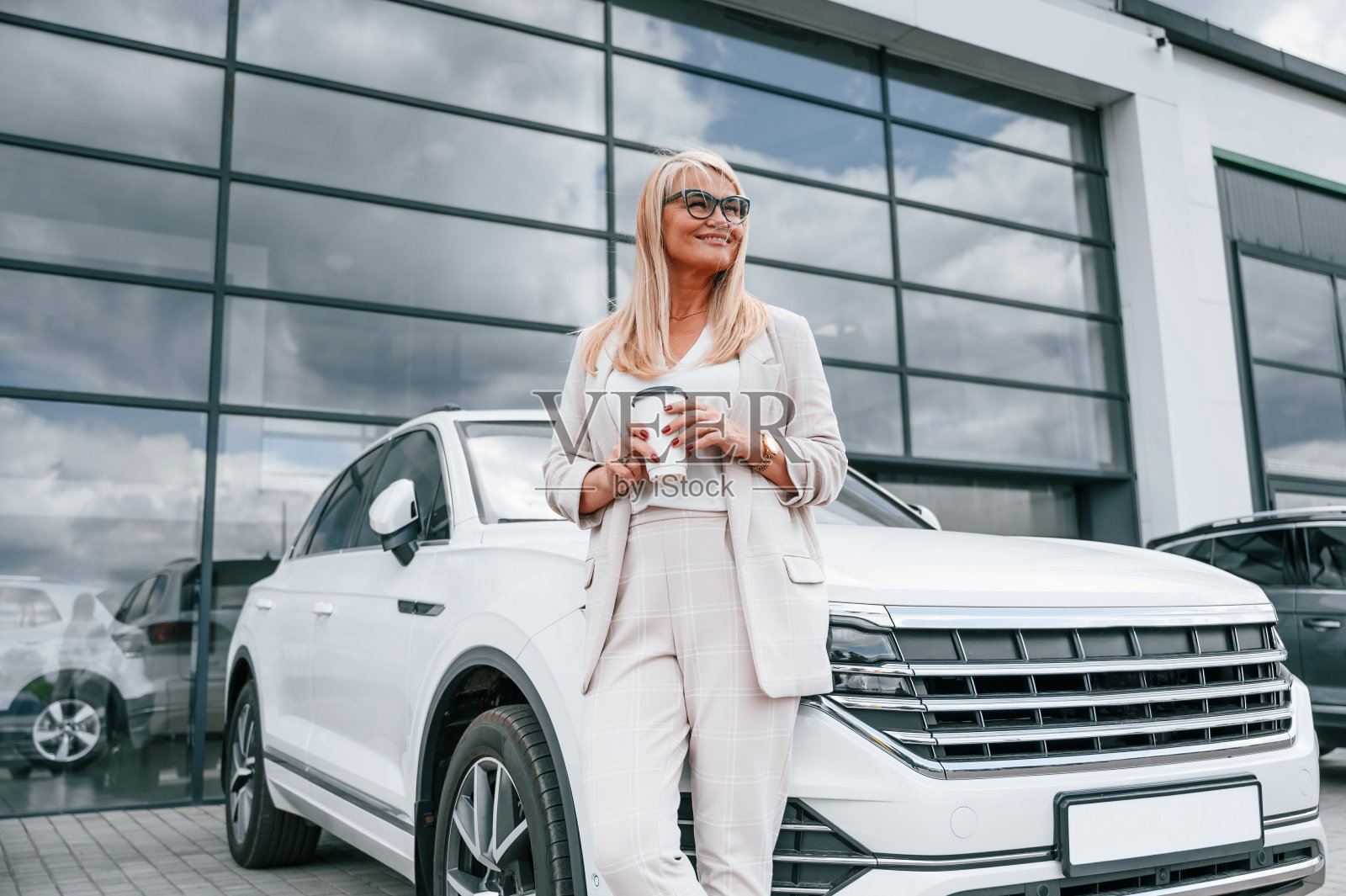 咖啡休息。穿白色正装的女人在汽车经销店里照片摄影图片