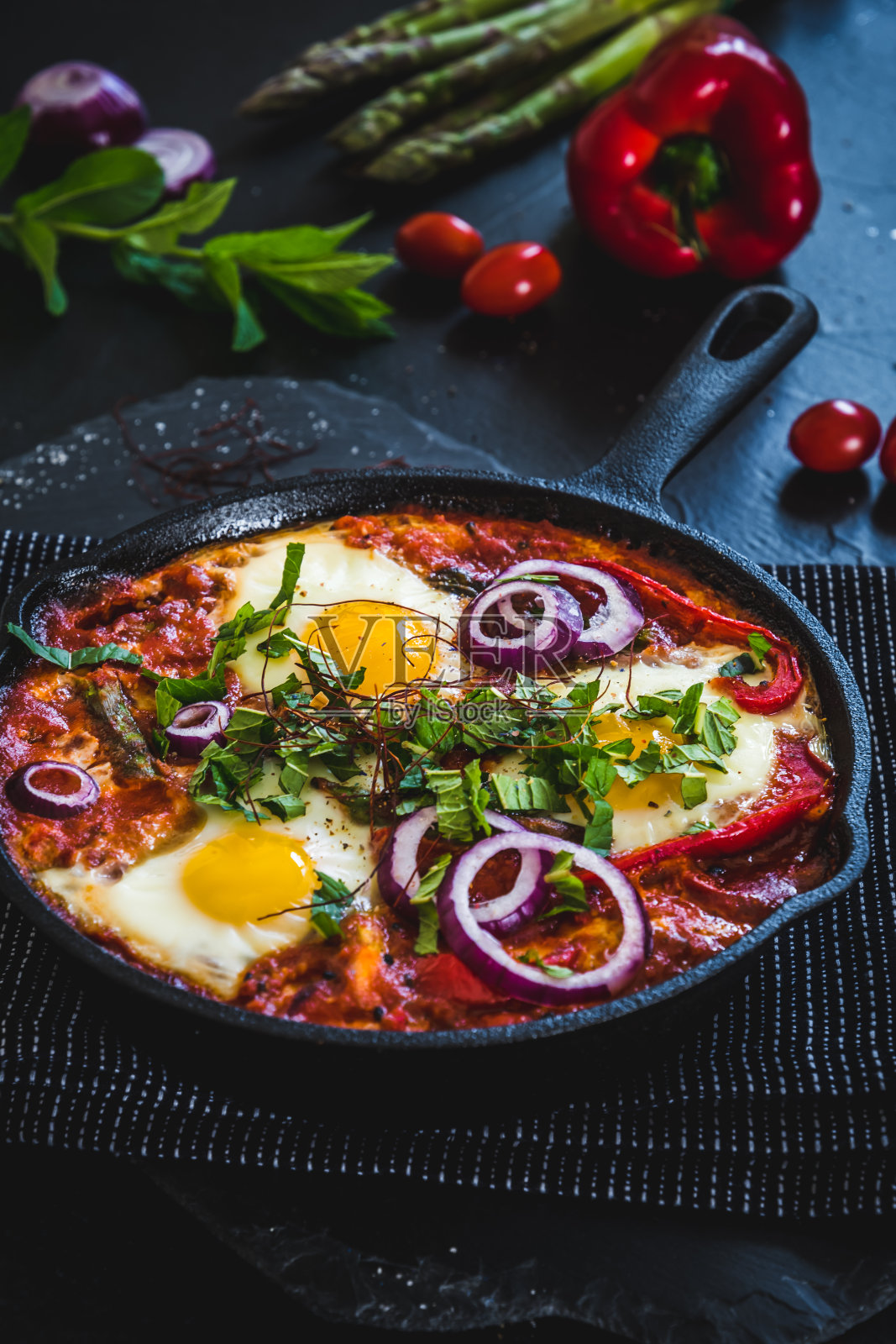 铁锅里的沙克舒卡。中东传统菜肴。鸡蛋配番茄，甜椒，蔬菜和香草，鸡蛋单面煎。垂直的。照片摄影图片