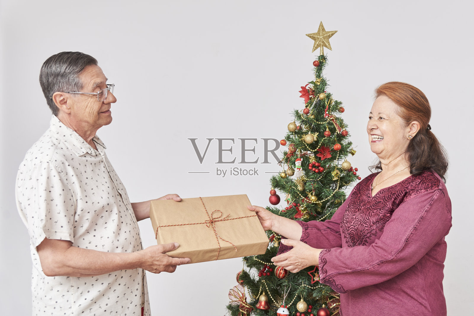 老夫妇在家里庆祝节日，他给她一份圣诞礼物照片摄影图片