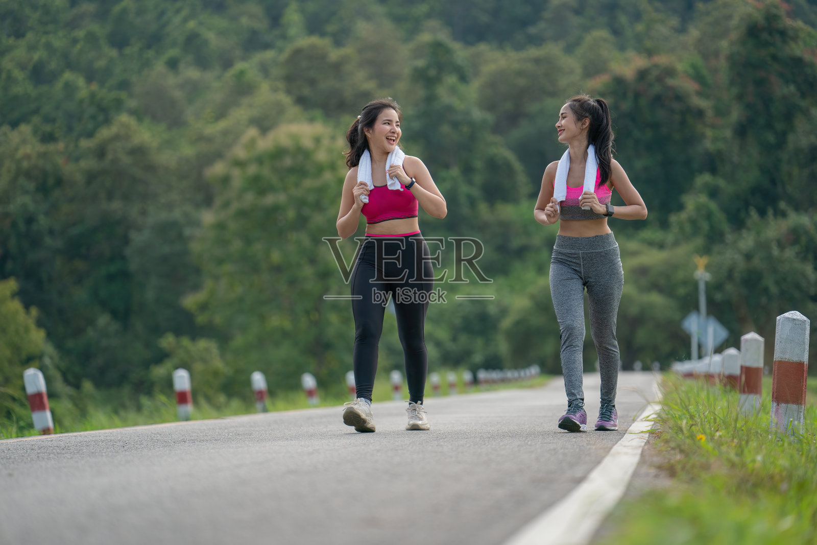 两个亚洲女性走在路上，在一个公园里，她们休息，促进健康，迷人的亚洲女性锻炼，微笑。照片摄影图片