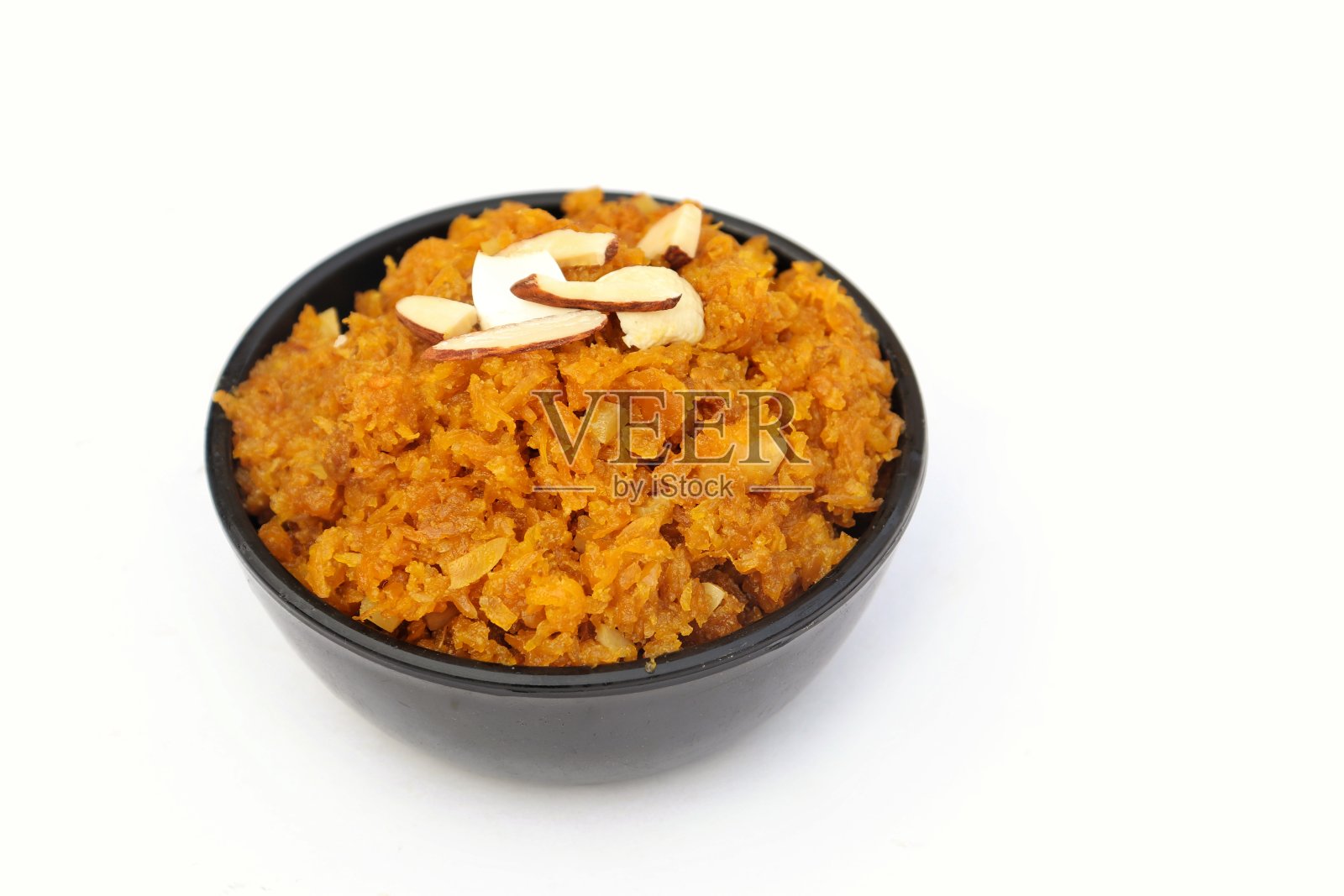 加贾尔卡哈尔瓦配杏仁和腰果在一个黑色碗孤立的白色背景与复制空间，胡萝卜哈尔瓦甜甜点食品照片摄影图片