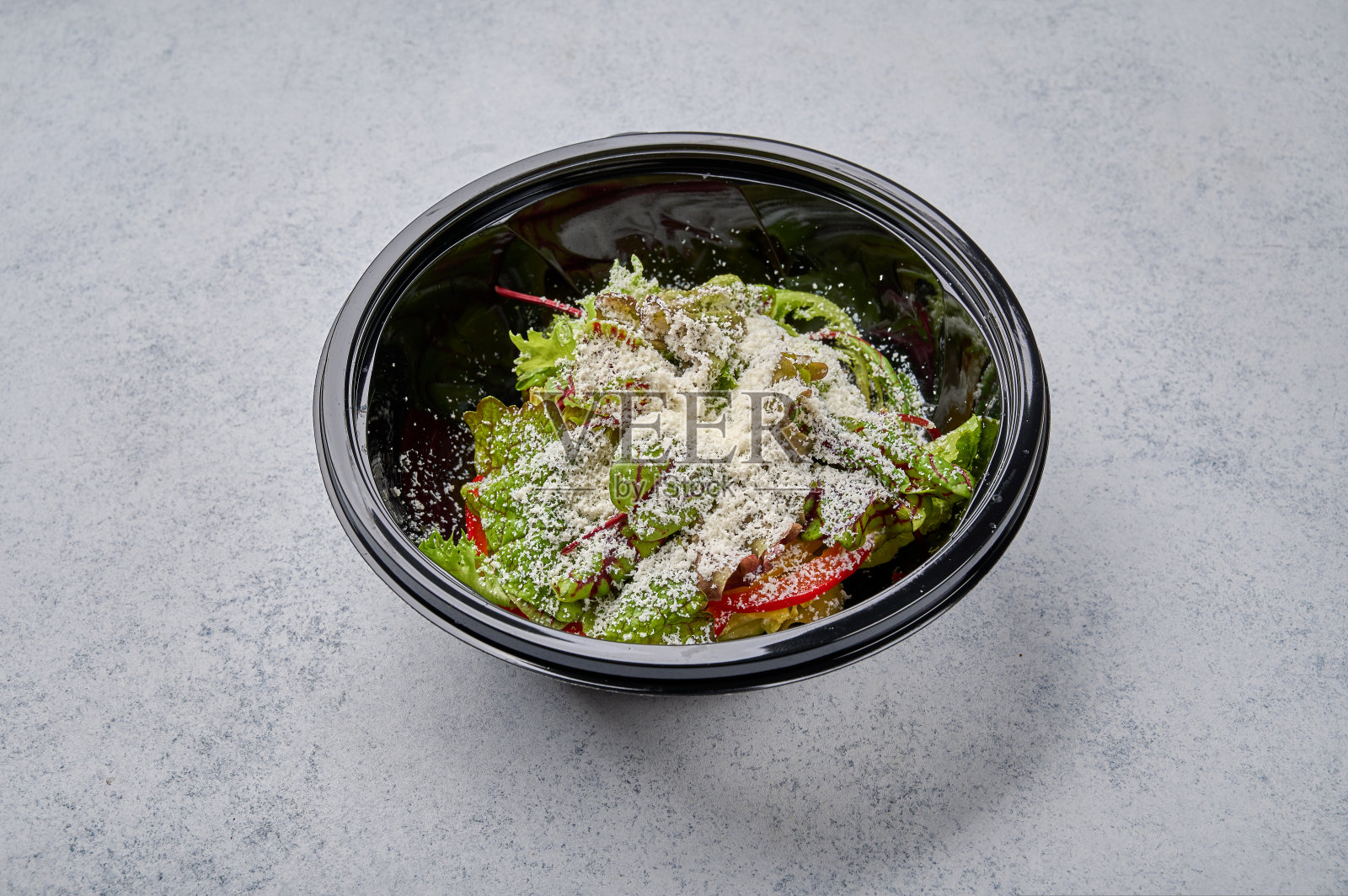 新鲜蔬菜和奶酪沙拉装在黑色塑料容器里照片摄影图片