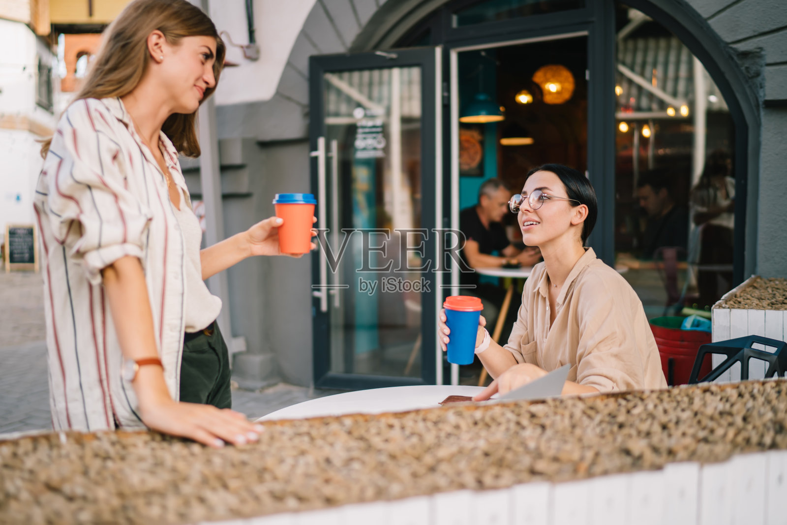 漂亮的女同学在周末聚会时在路边的自助餐厅用咖啡饮料交流，漂亮的女同学喜欢在聚会时进行现场社交和轻松的交谈照片摄影图片
