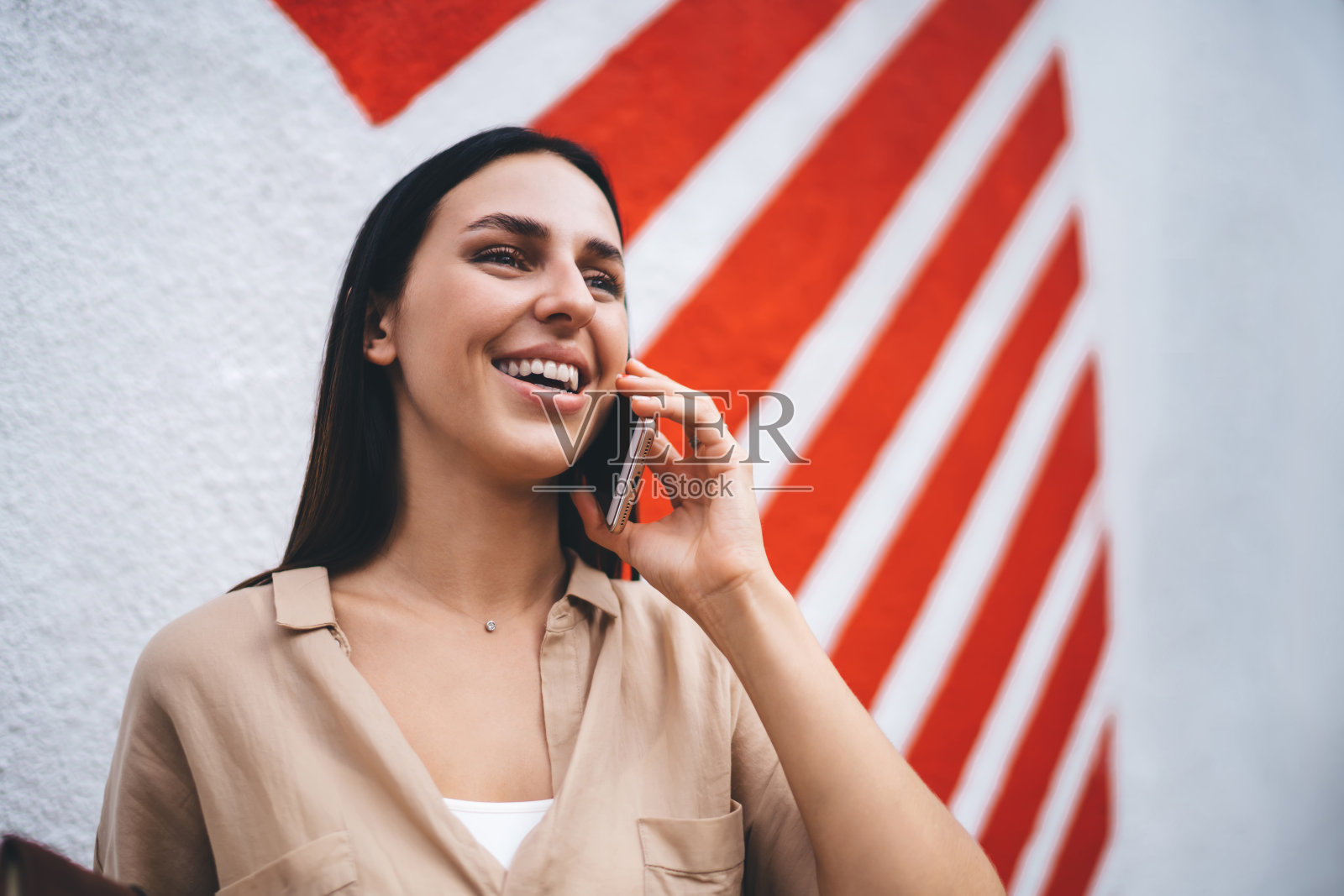 快乐的白人女子20岁，在漫游中享受积极的手机通话，快乐的褐发潮女孩连接4g互联网与朋友进行国际交流照片摄影图片